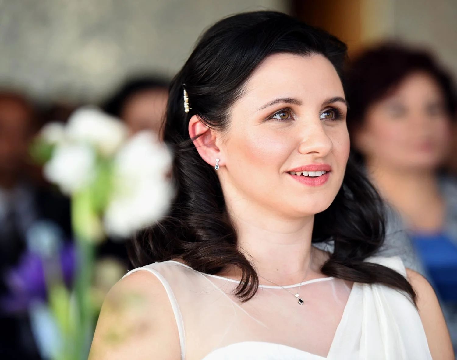 A bride at her ceremony, white lilies behind her, Kensington Roof Gardens