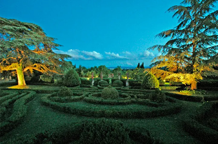 A formal Italian garden illuminated at twilight