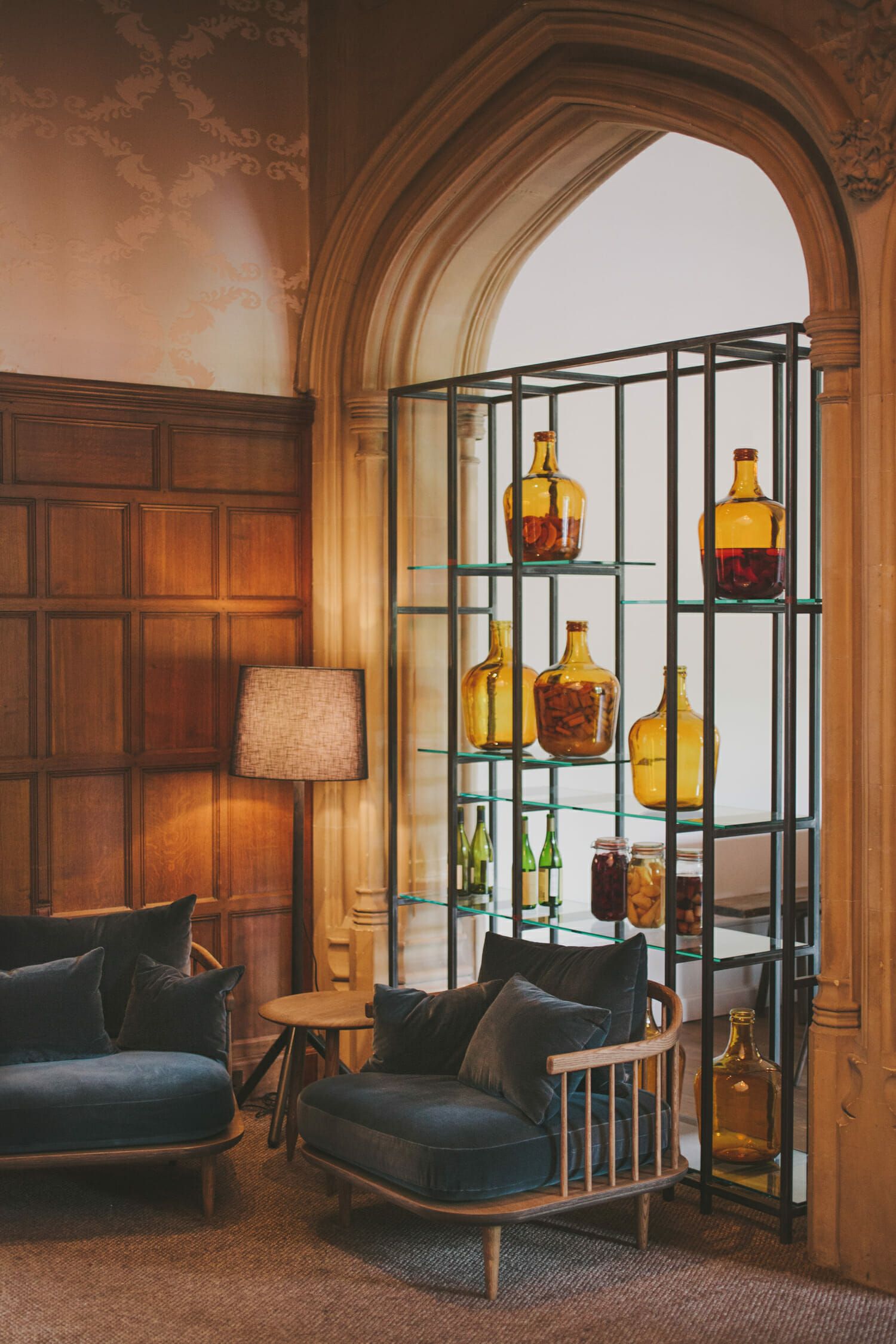 A panelled sitting room with an arched window and shelves of amber glass bottles