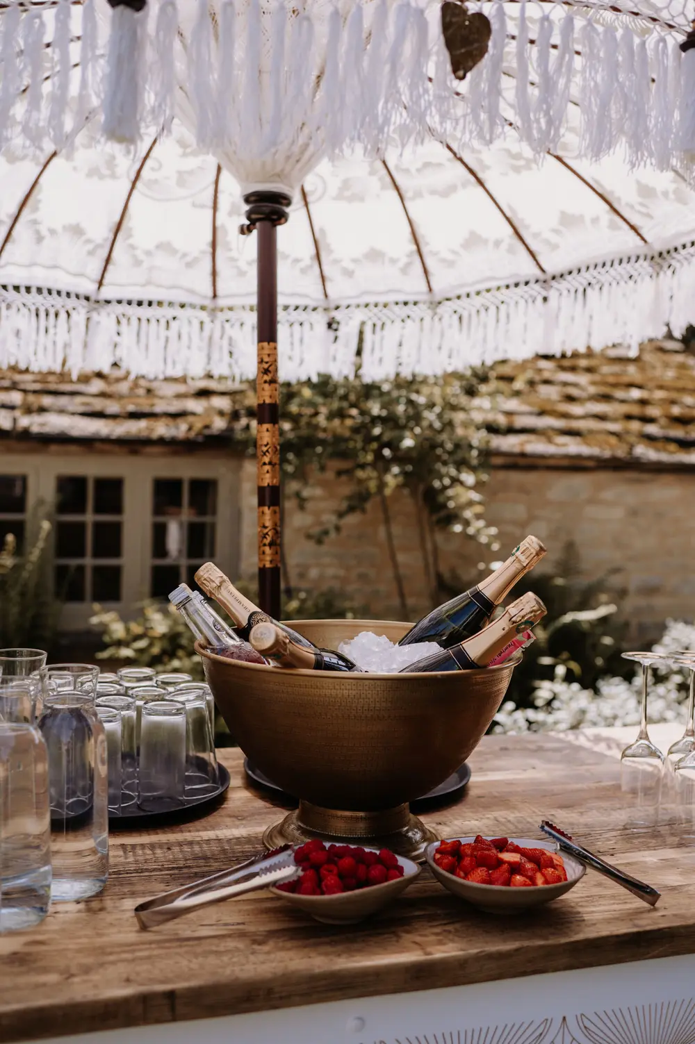 A drinks reception at Caswell House, set beneath a parasol against the Cotswold stone