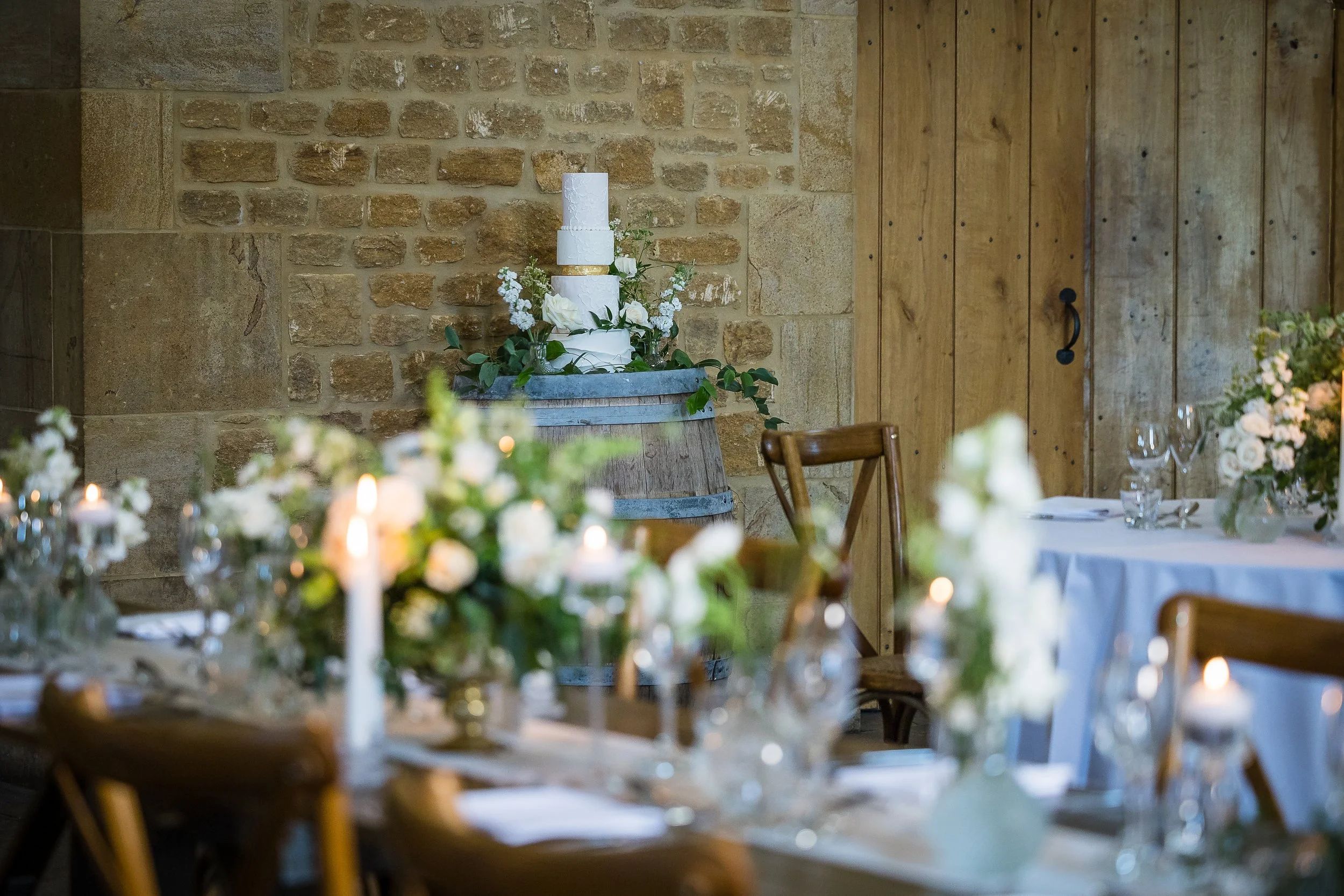 A wedding cake and candlelit table in the barn