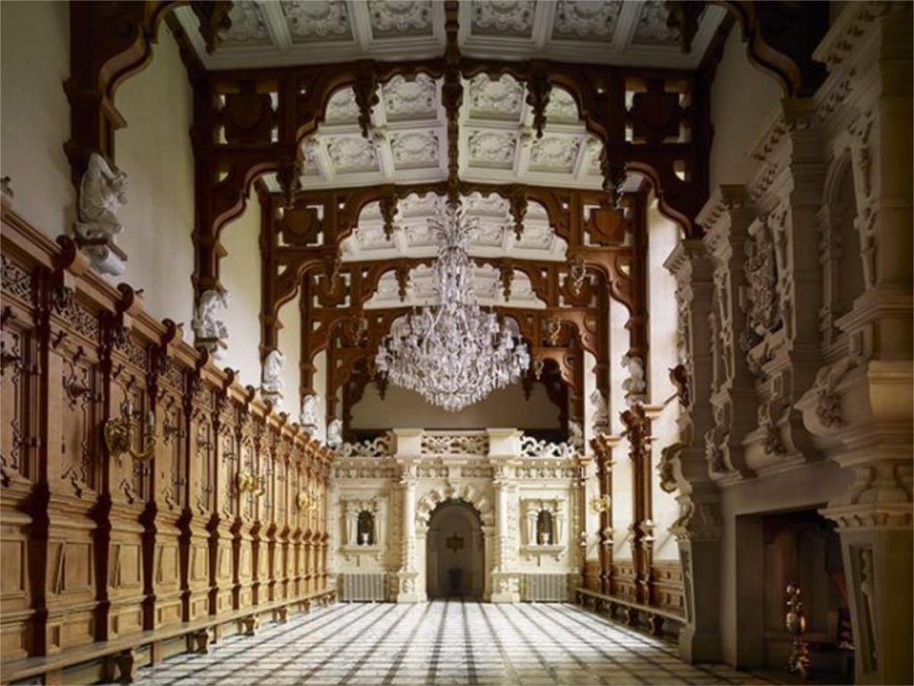 An opulent state room with richly carved oak panelling and a grand arched doorway