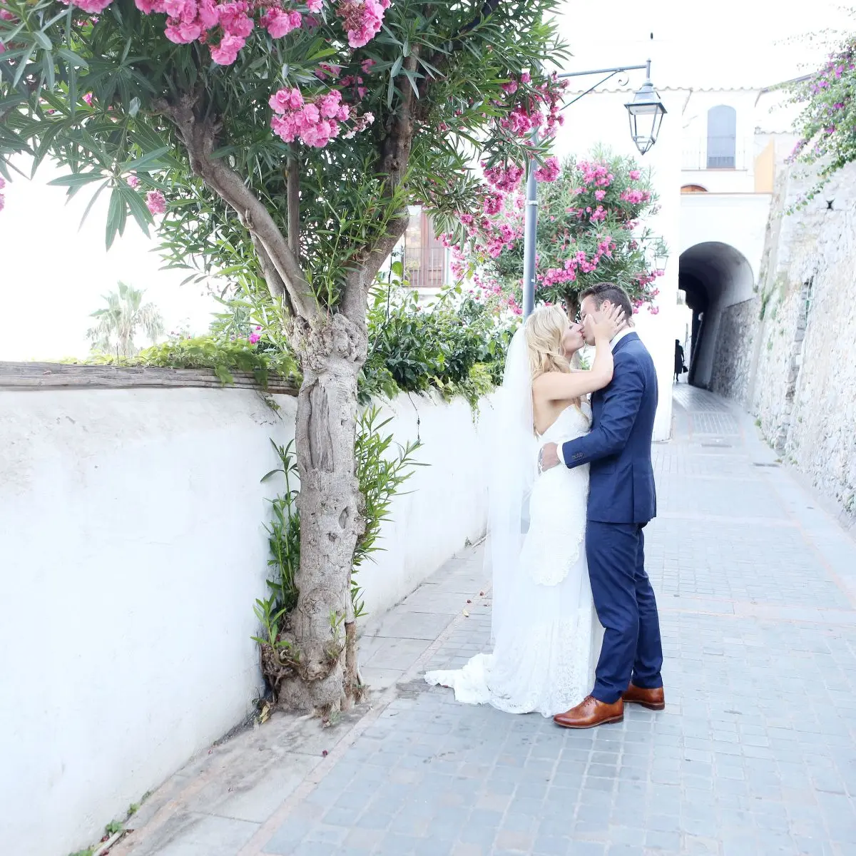 A couple kissing under a bougainvillea-covered tree in an Amalfi Coast lane