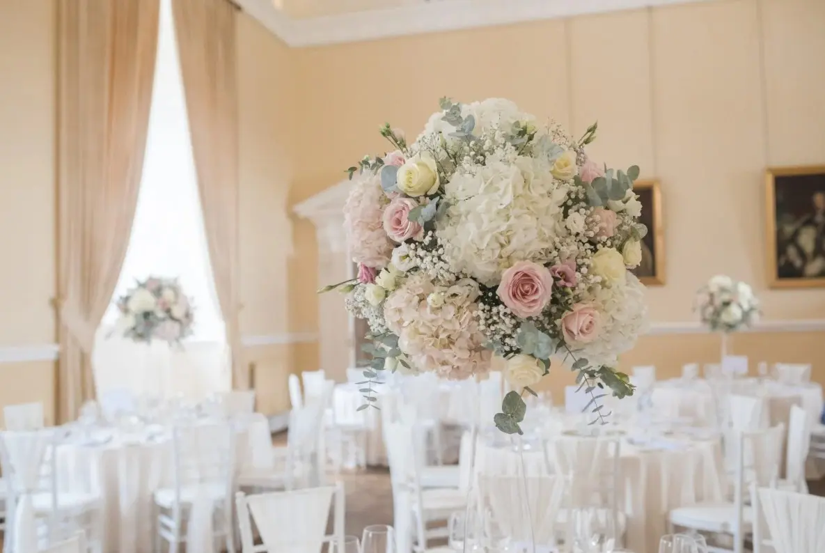 The Great Hall set for a ceremony with white chairs and tall florals