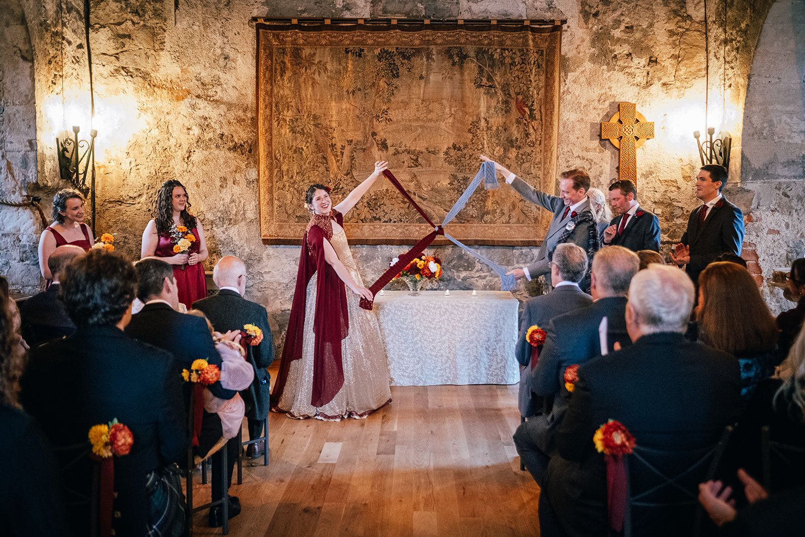 A handfasting ceremony indoors, the couple joined beneath tartan before their guests
