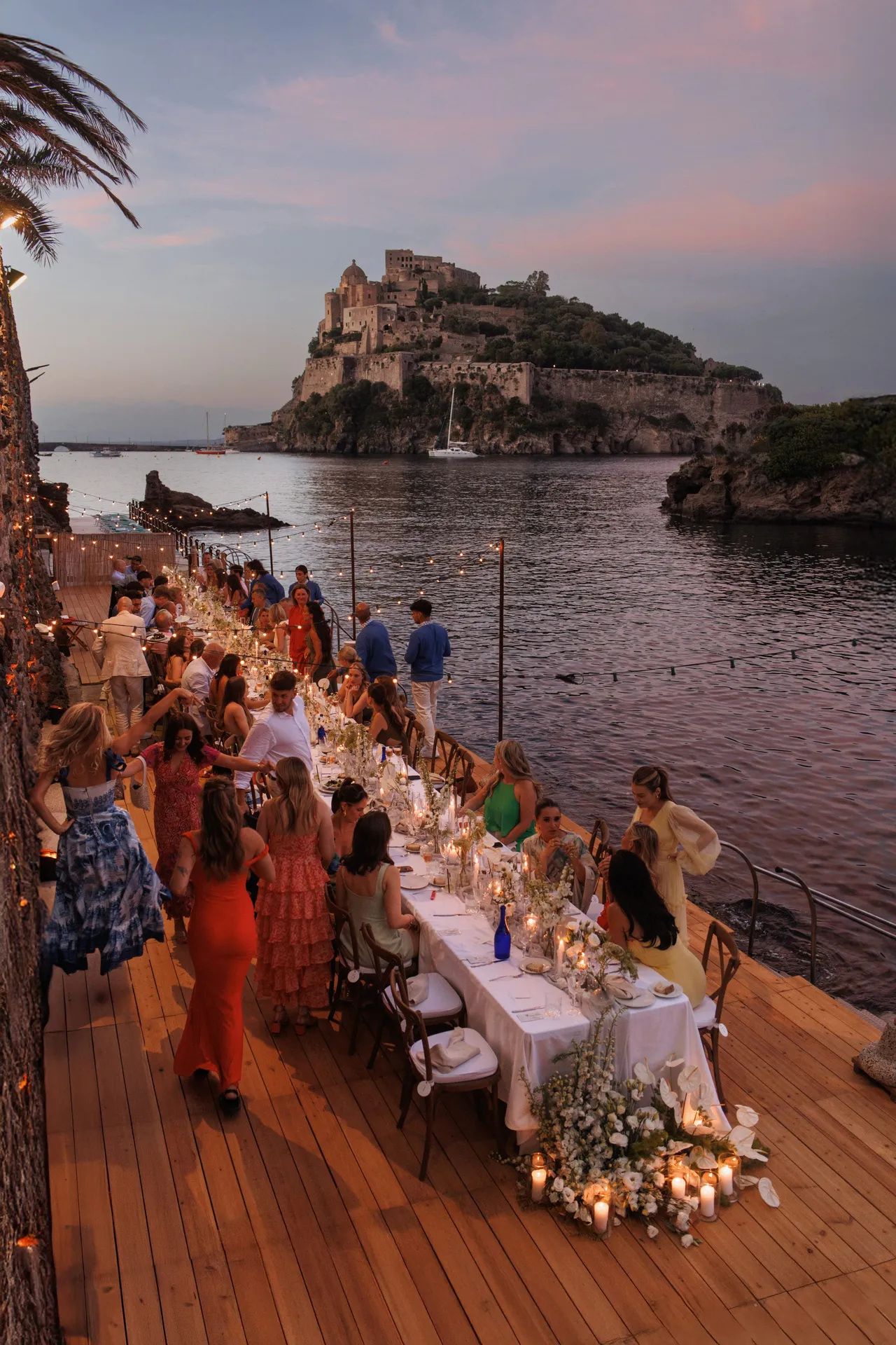The same deck at sunset, dinner served, the castle in silhouette