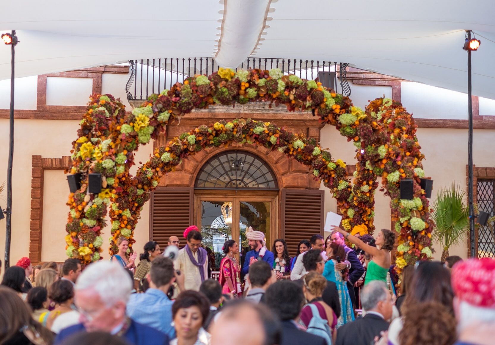 Ceremony beneath an autumnal floral arch at the castle entrance, Castello di Solfagnano, Perugia, Italy