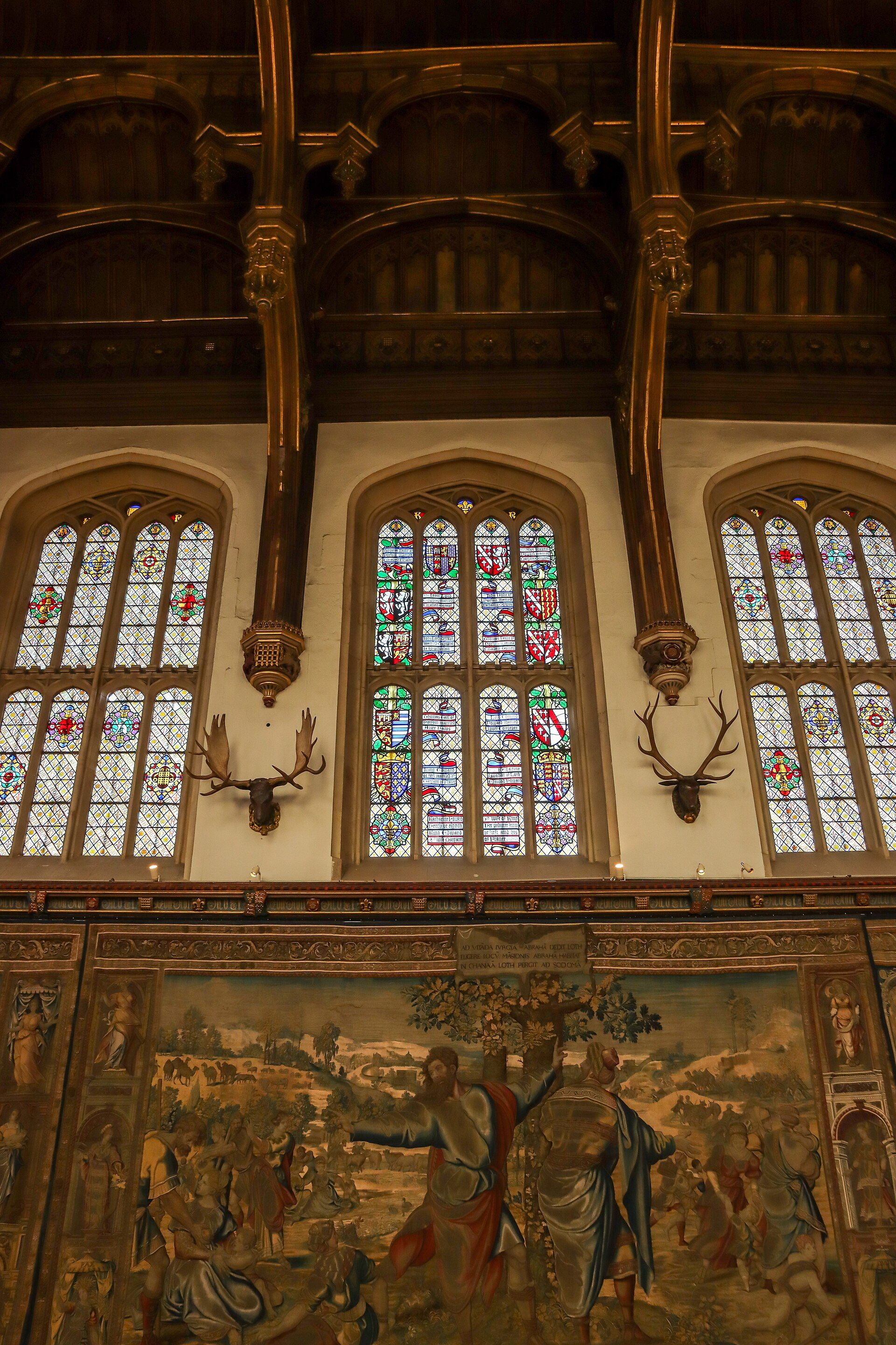 Tudor tapestries and mounted antlers beneath the Great Hall's stained-glass windows