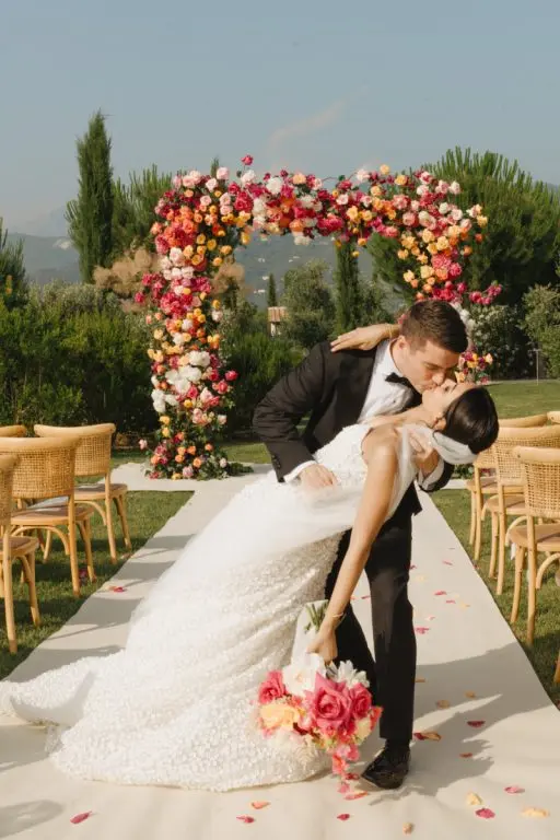 Wedding ceremony kiss at flower arch on the estate lawns, Paradis Pietrasanta