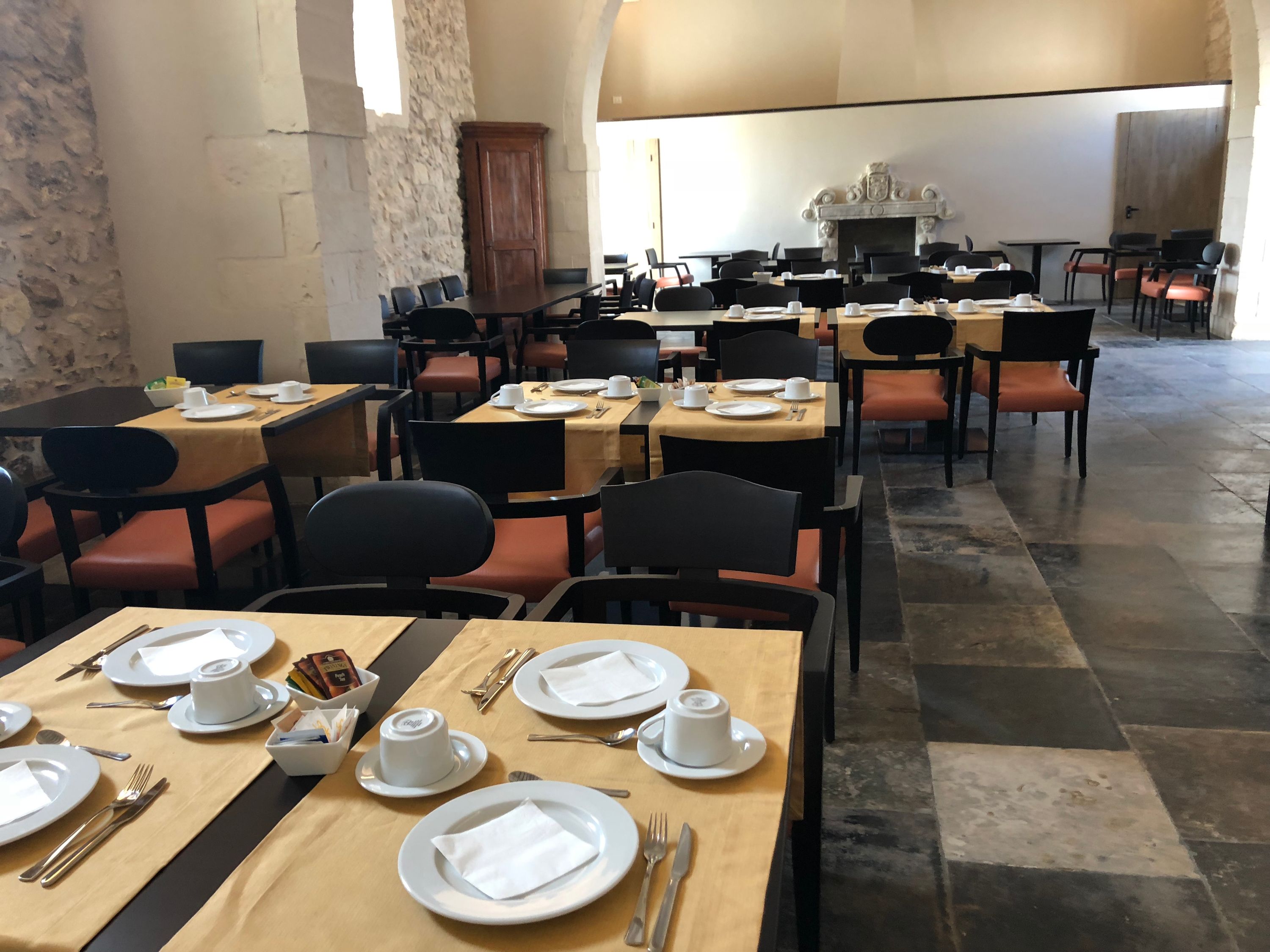 The dining room set for breakfast, exposed stone and warm light