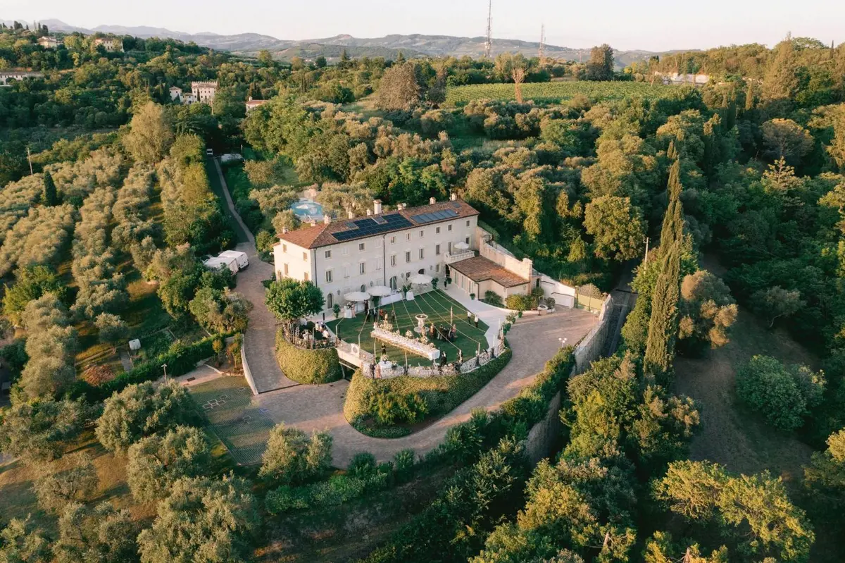 Drone aerial of a grand Veneto country villa estate at golden hour, an outdoor reception laid on the lawn