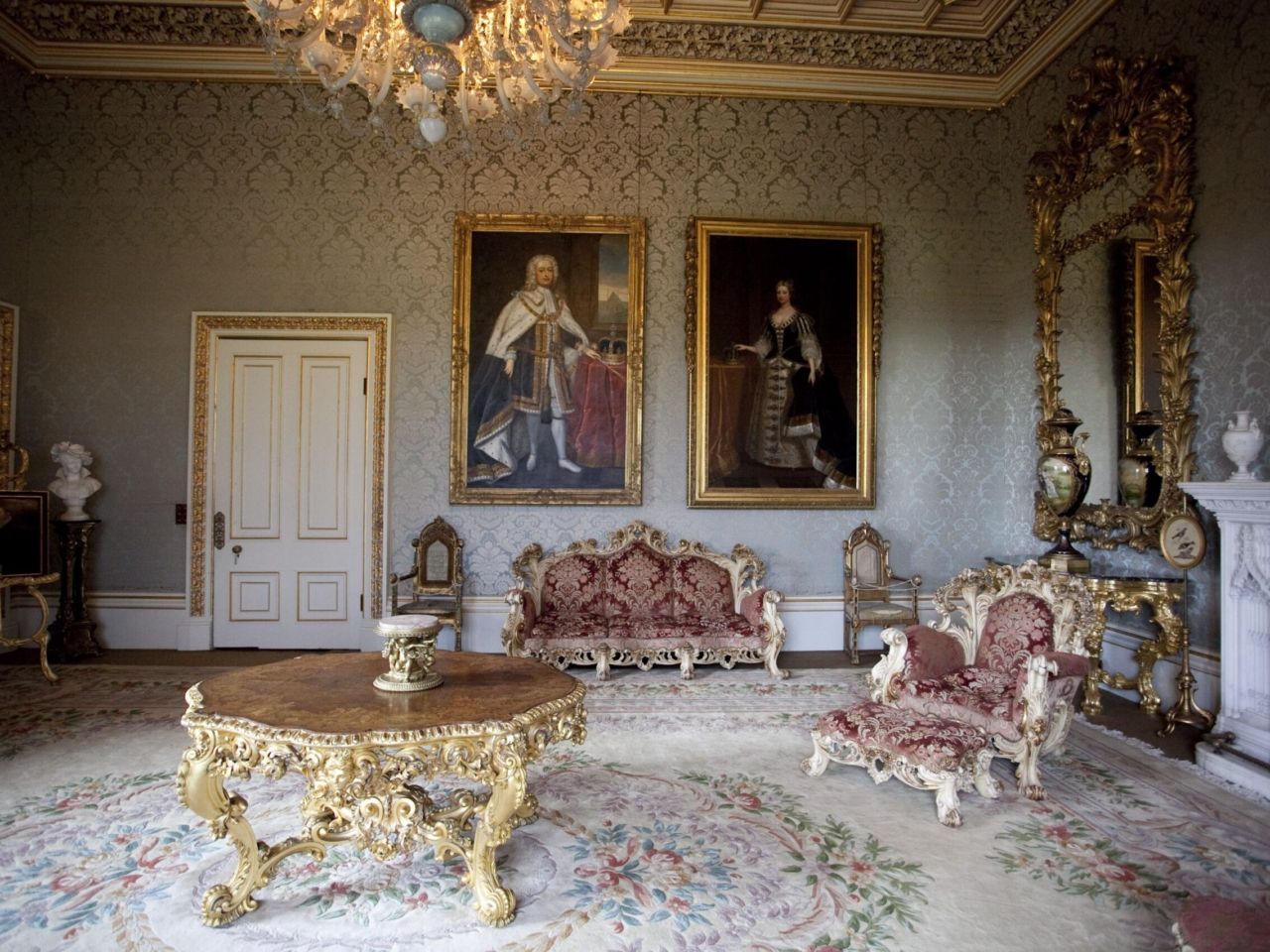A gilded reception room hung with family portraits, gold-framed furniture and a chandelier