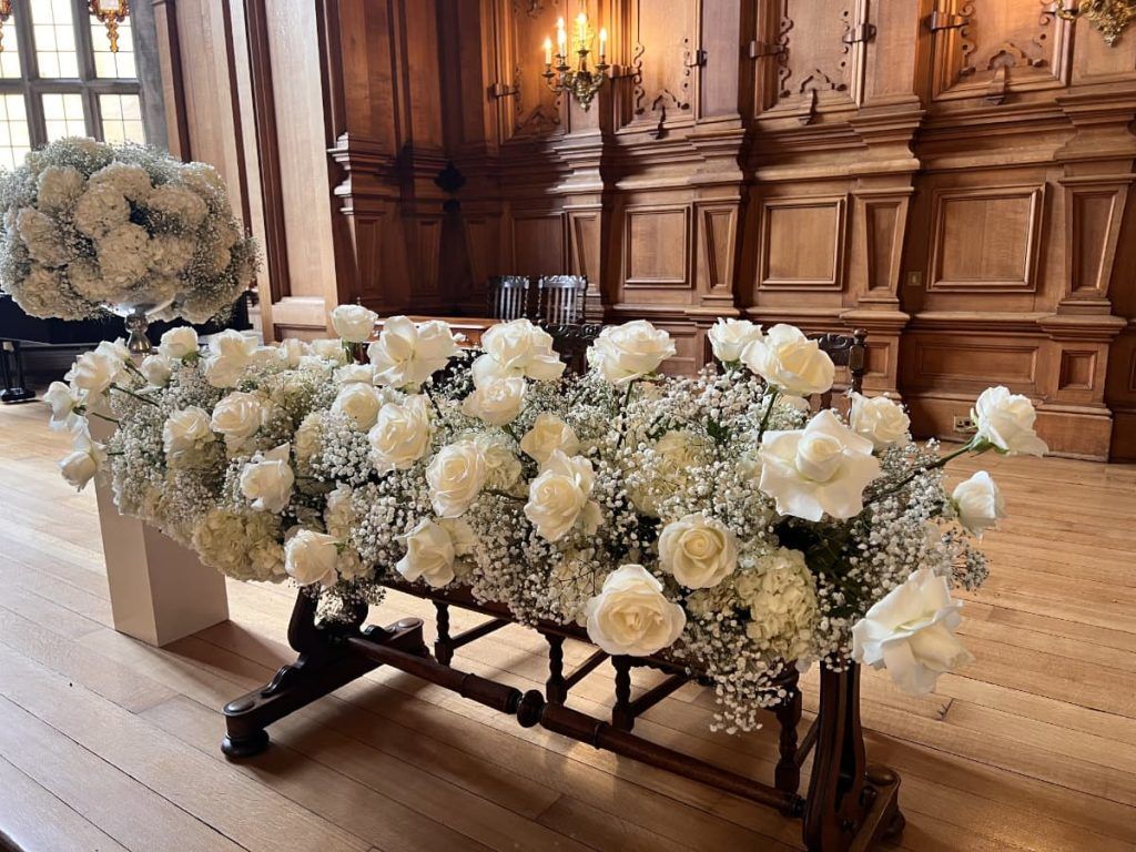 A cascading white rose and hydrangea arrangement in a wood-panelled room