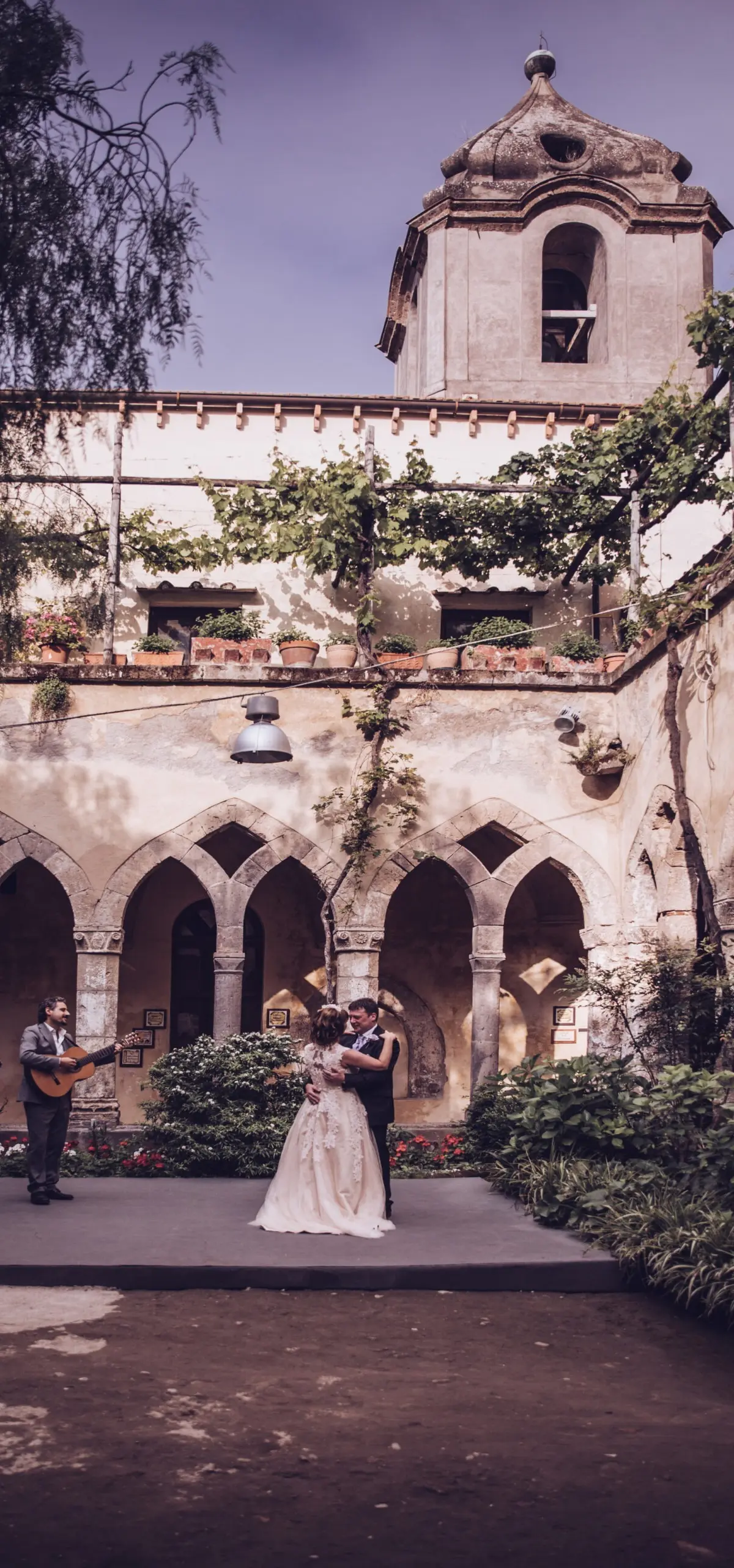 A couple dancing in a stone cloister to two live guitarists