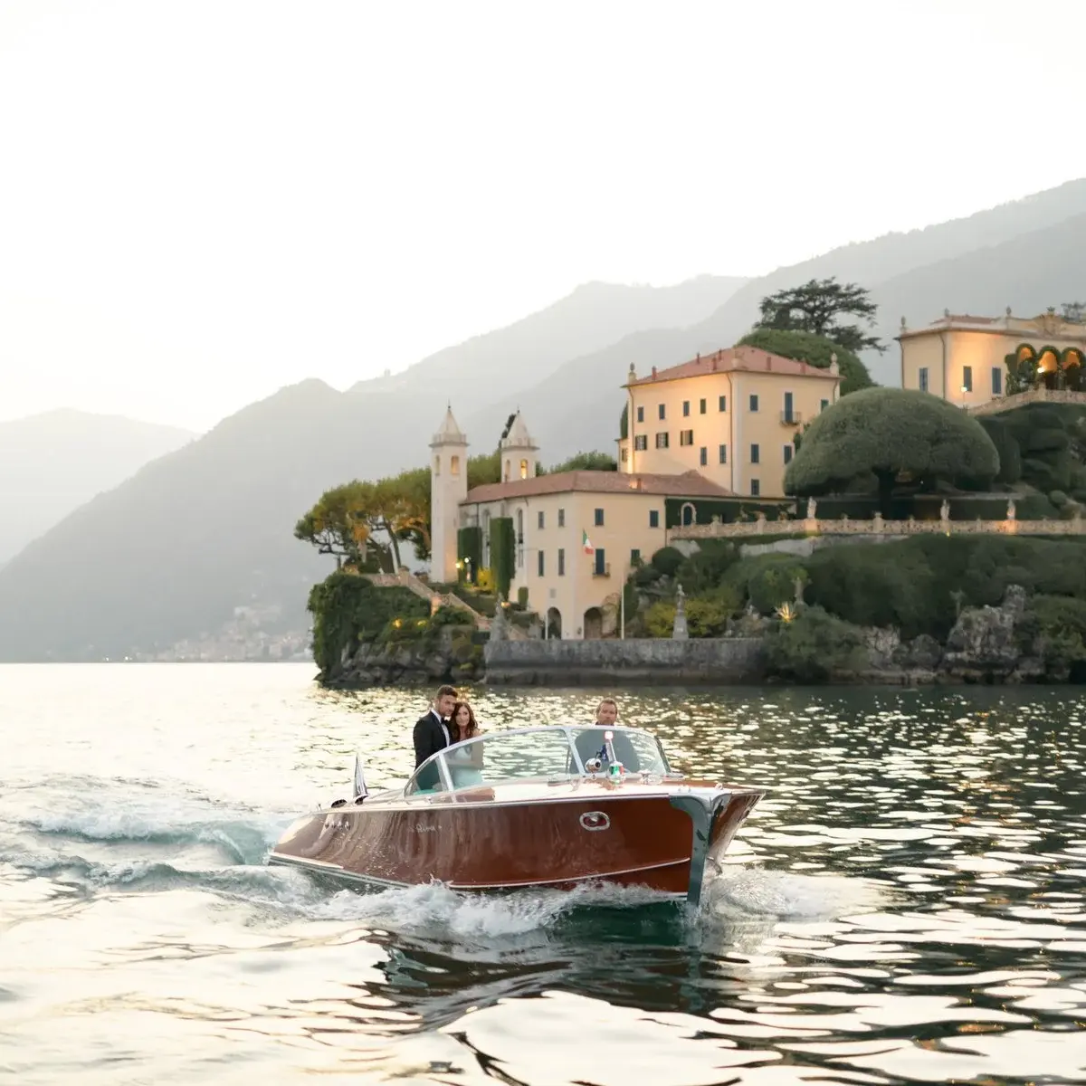 A wooden launch running past Villa del Balbianello at dusk