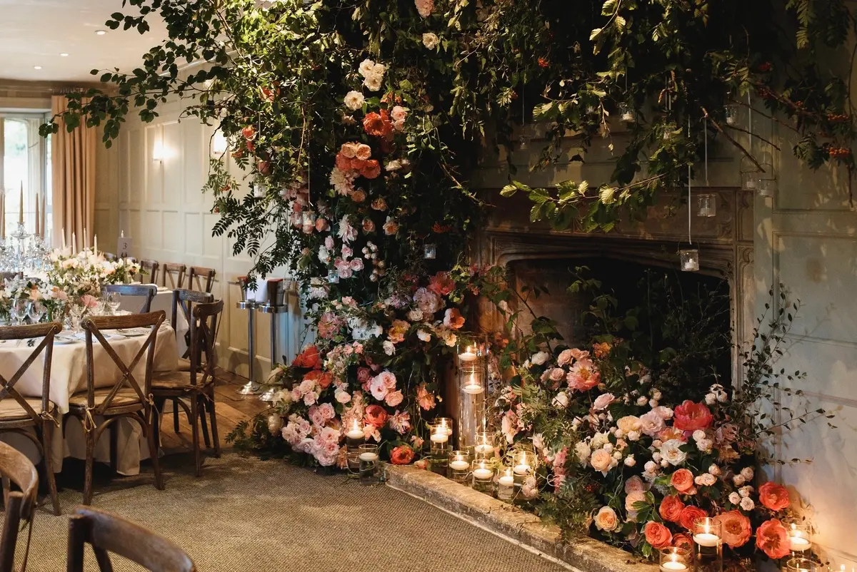 Garden rose and dahlia climb from the hearth to the ceiling, Barnsley House, McQueens Flowers, London, England