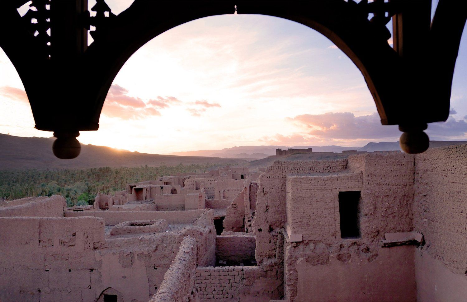The Drâa Valley at dusk, framed by a carved arch, Kasbah des Caïds, Agdz, Morocco