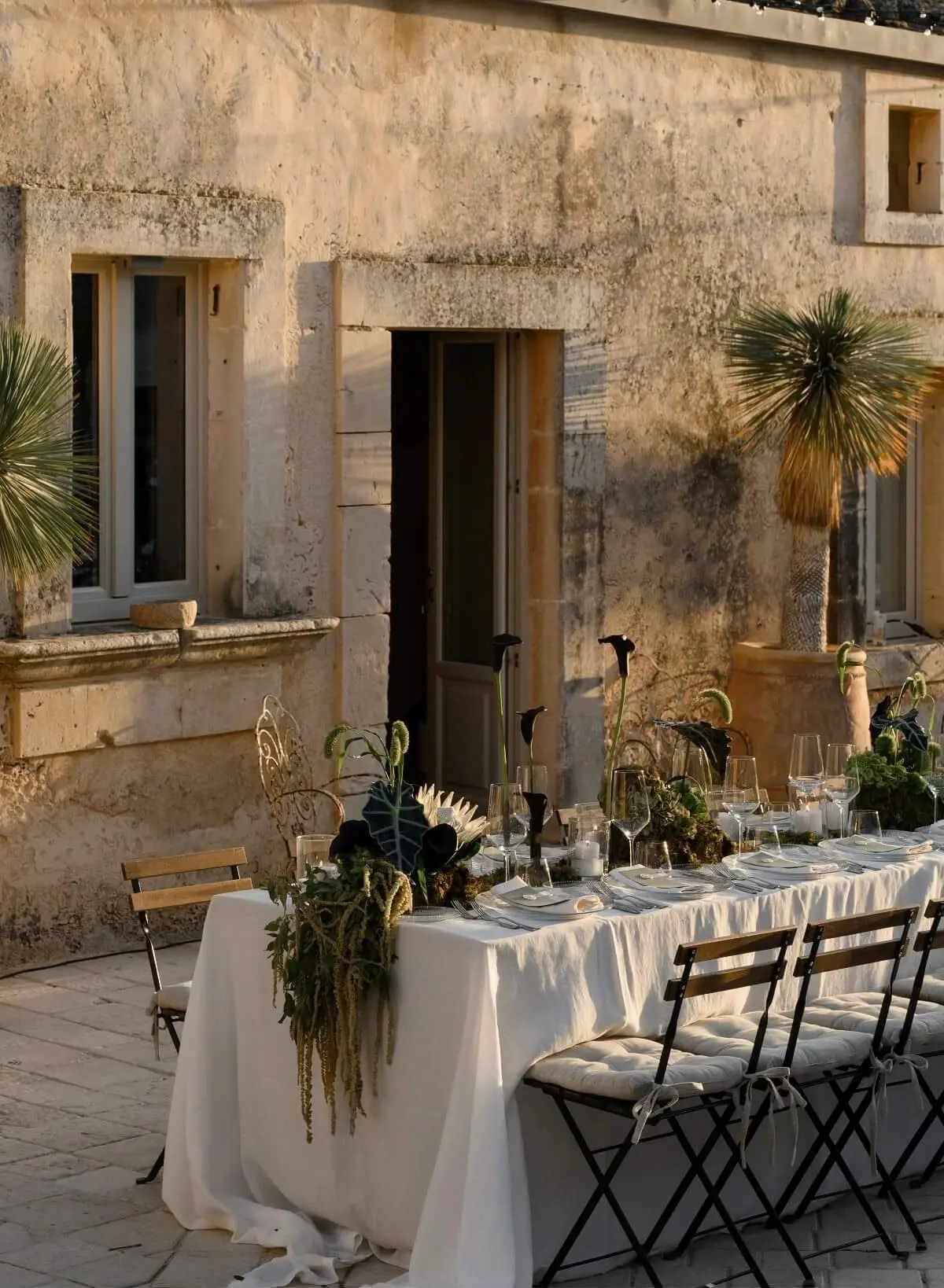 A long table laid outside a stone farmhouse in Sicily