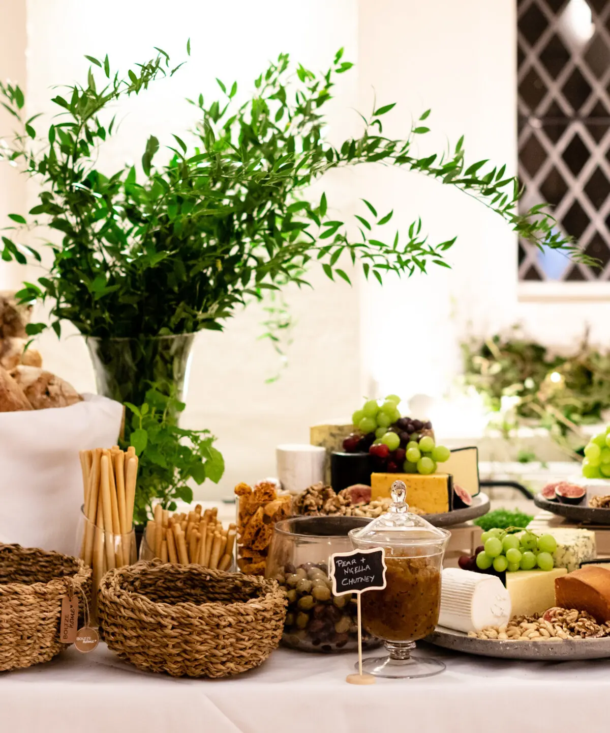A grazing board of breads, cheeses and greenery
