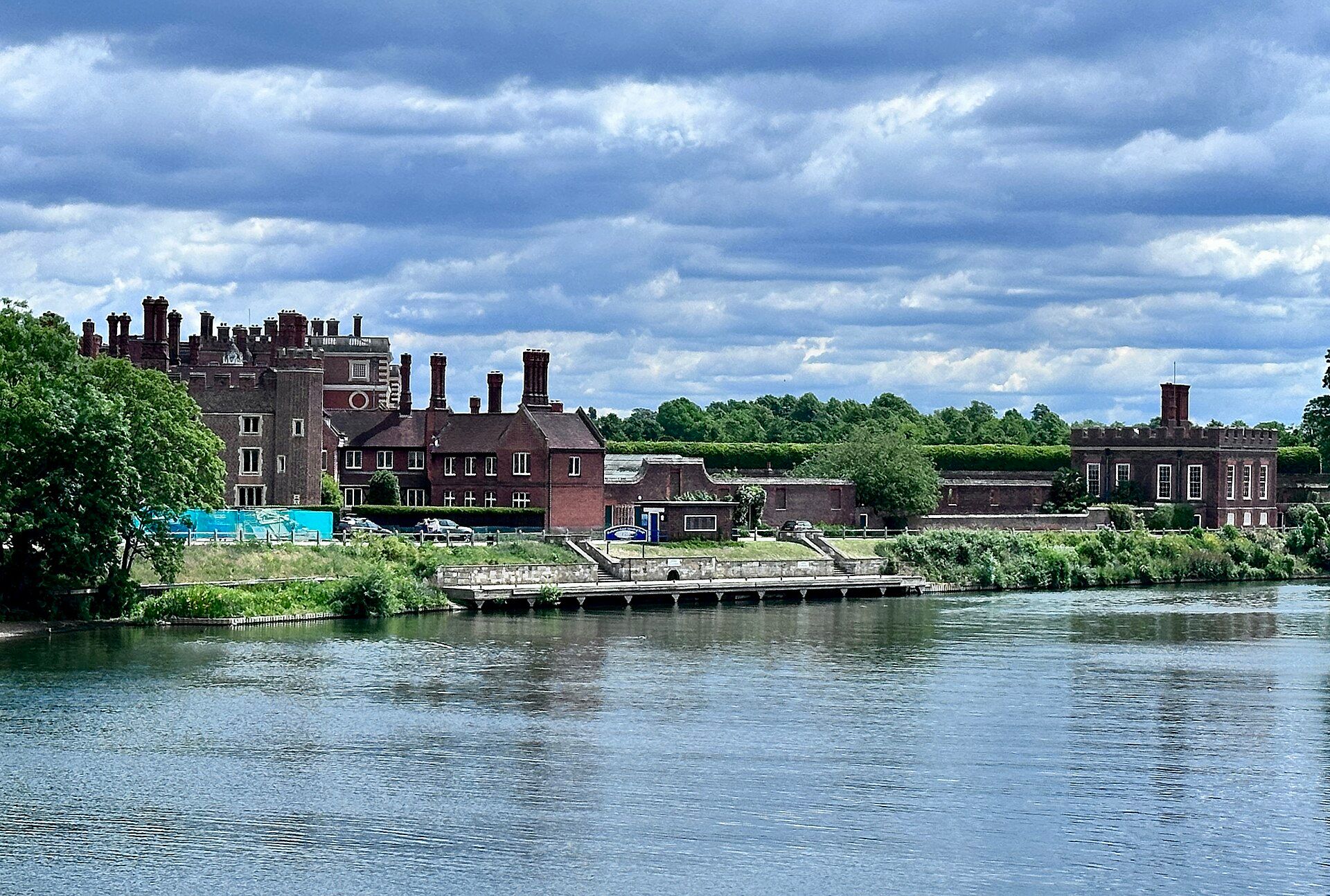The palace and its Tudor chimneys reflected in the River Thames beneath a wide sky, Hampton Court Palace, East Molesey, England