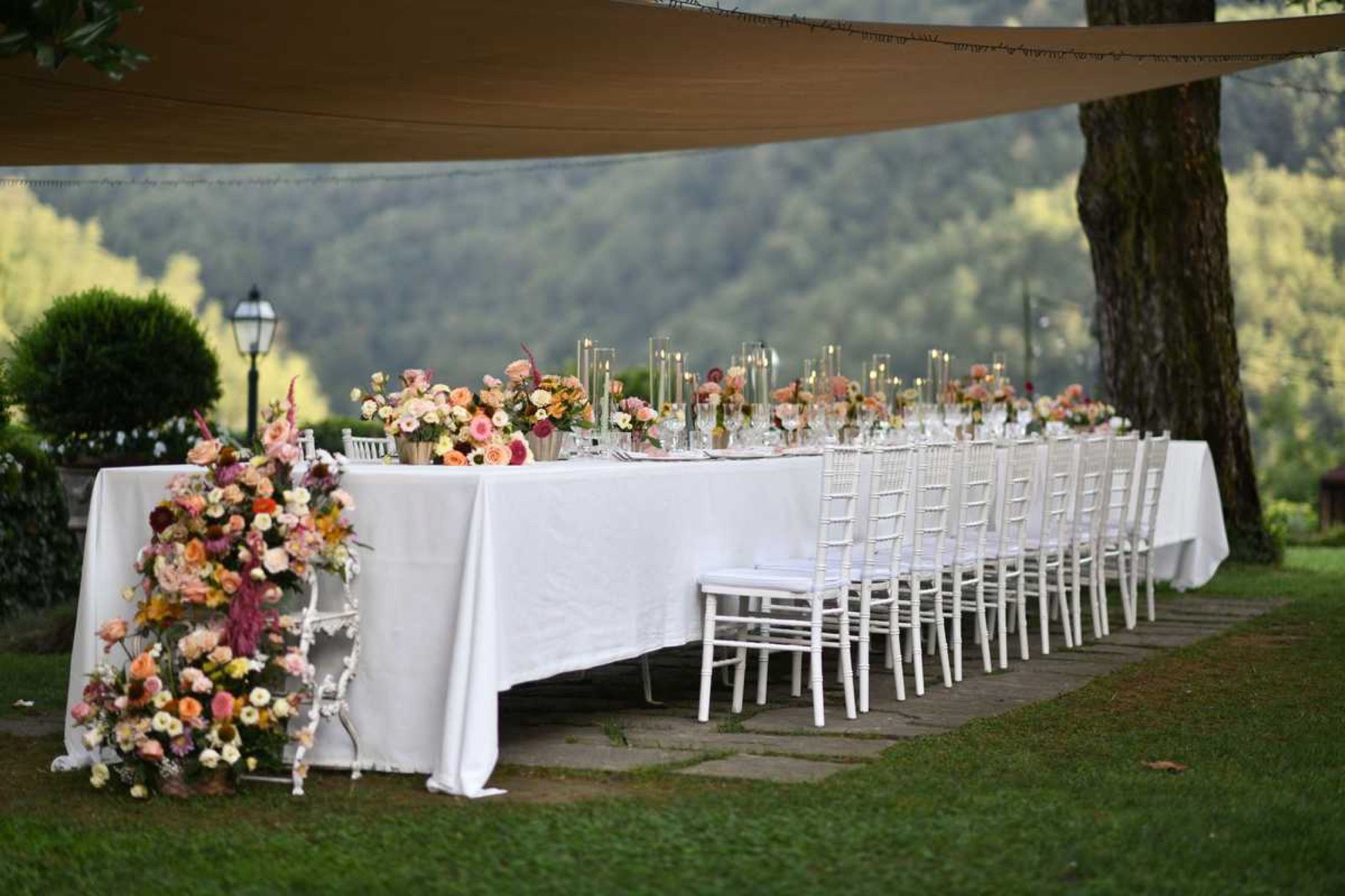 A long table dressed with flowers under the trees