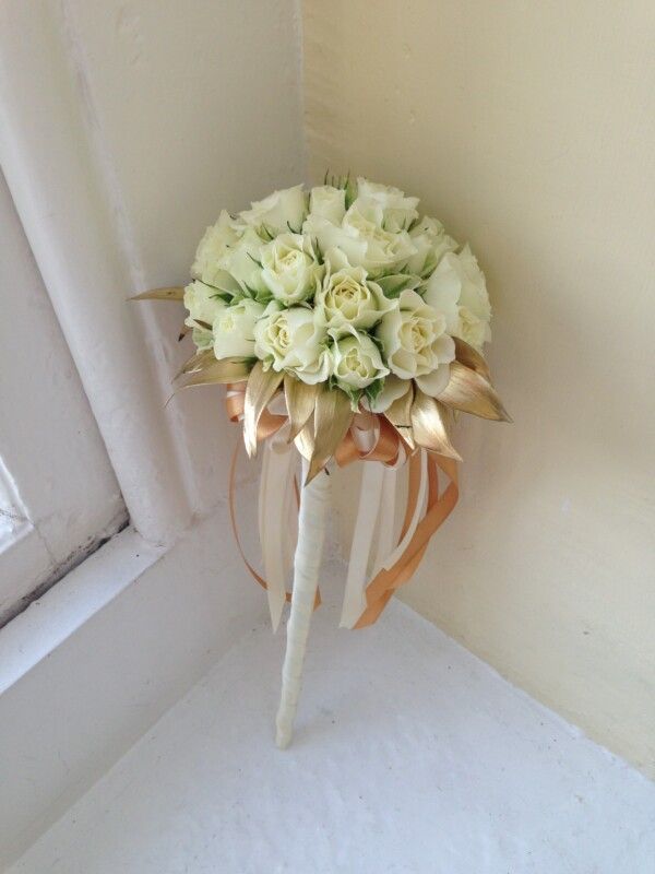 A cream bridal bouquet, finished with gold ribbon