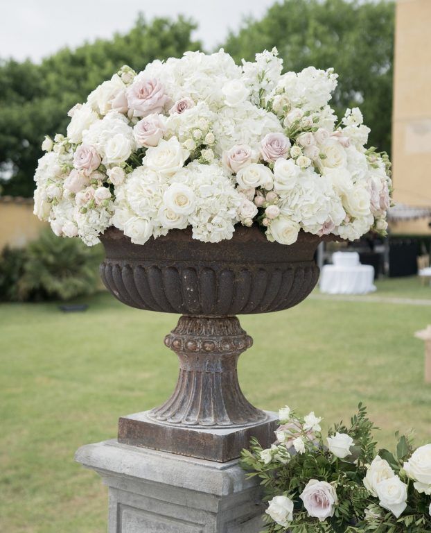 A white and blush urn, on a garden pedestal