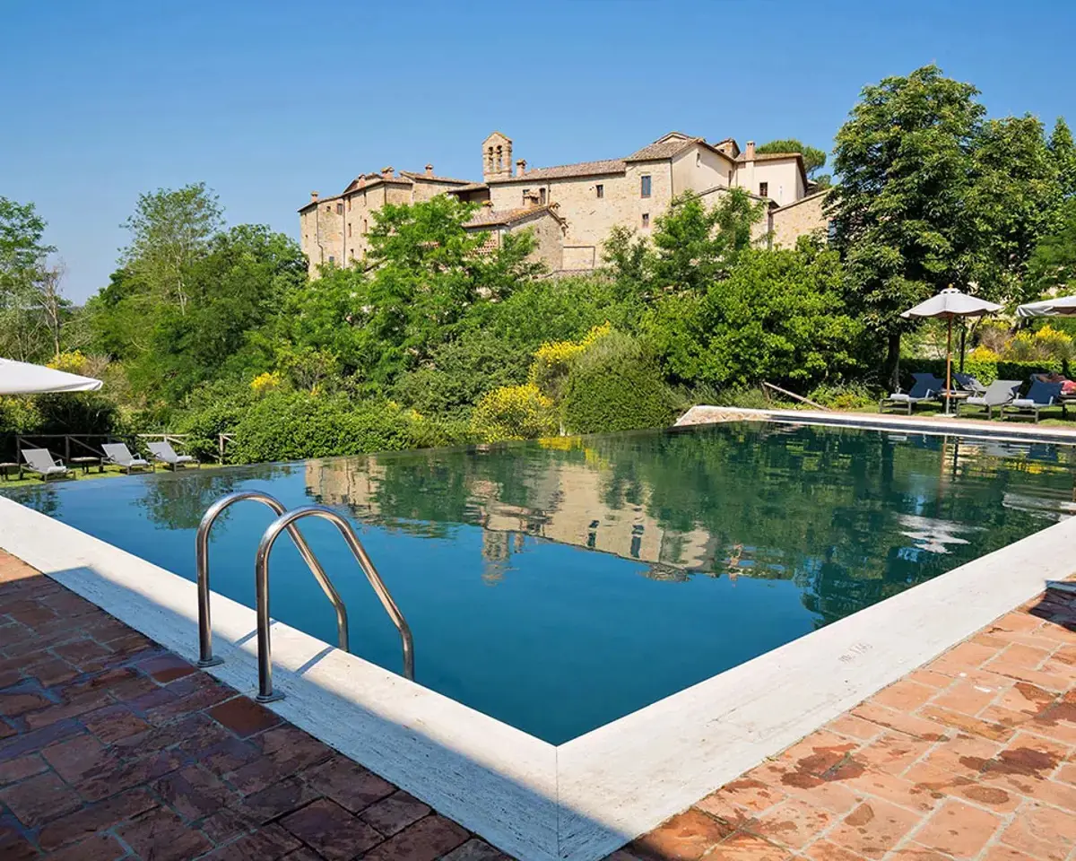 The cascading pool at Castel Monastero with the medieval castle reflected in the water
