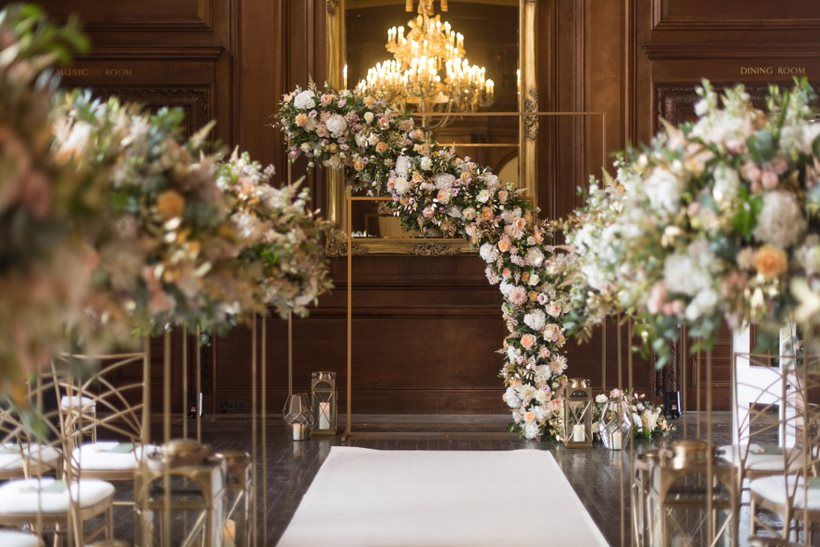 A candlelit ceremony arch in a wood-panelled room