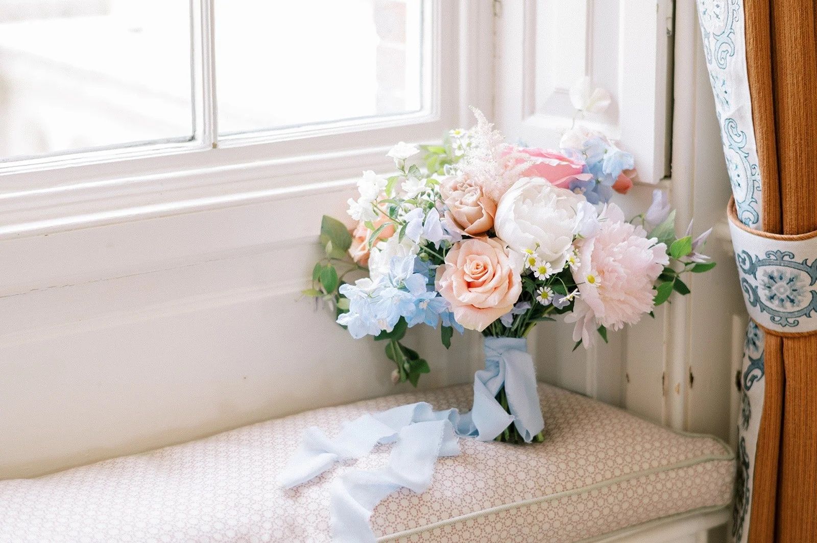 A bouquet of peony, sweet pea and delphinium, ribbon trailing