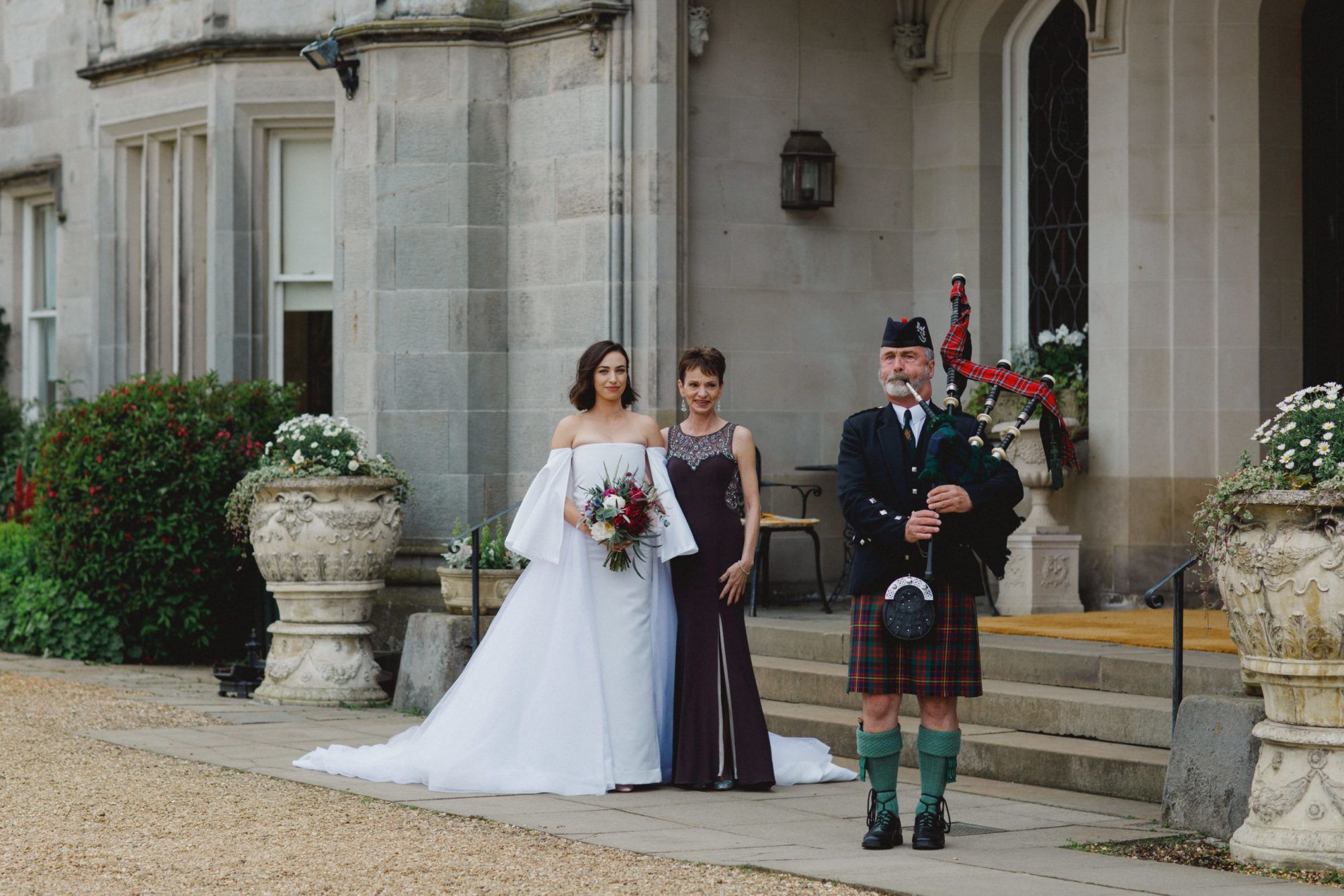 A bride and a kilted groom by the castle stone entrance steps