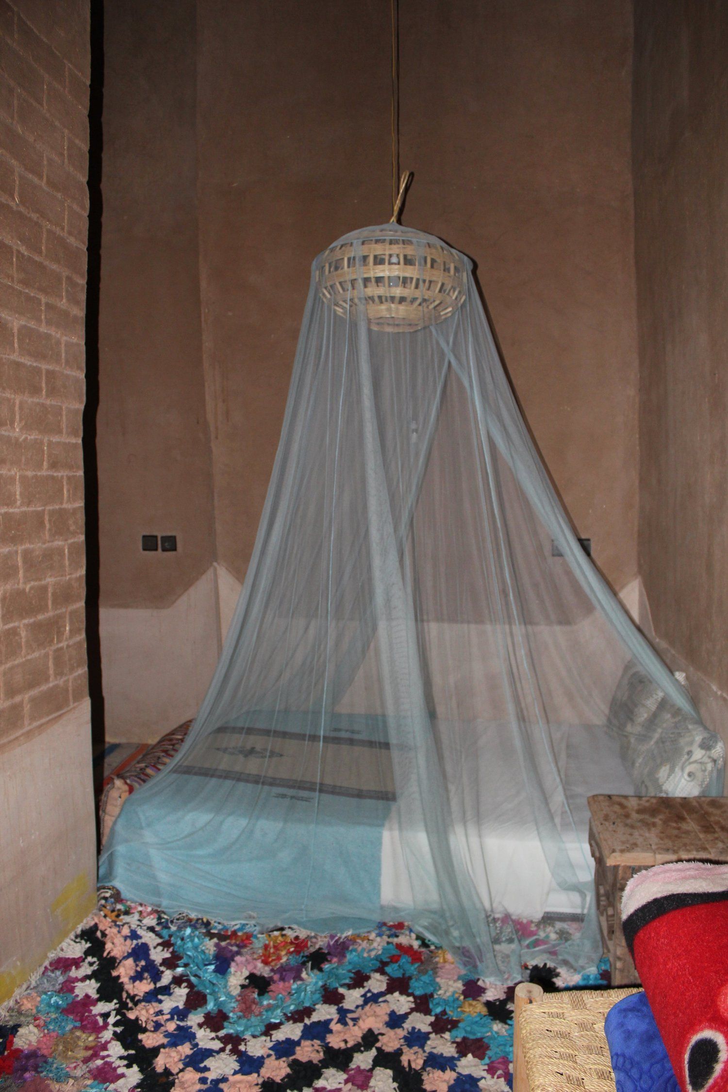 A bed beneath a canopy, behind rammed-earth walls