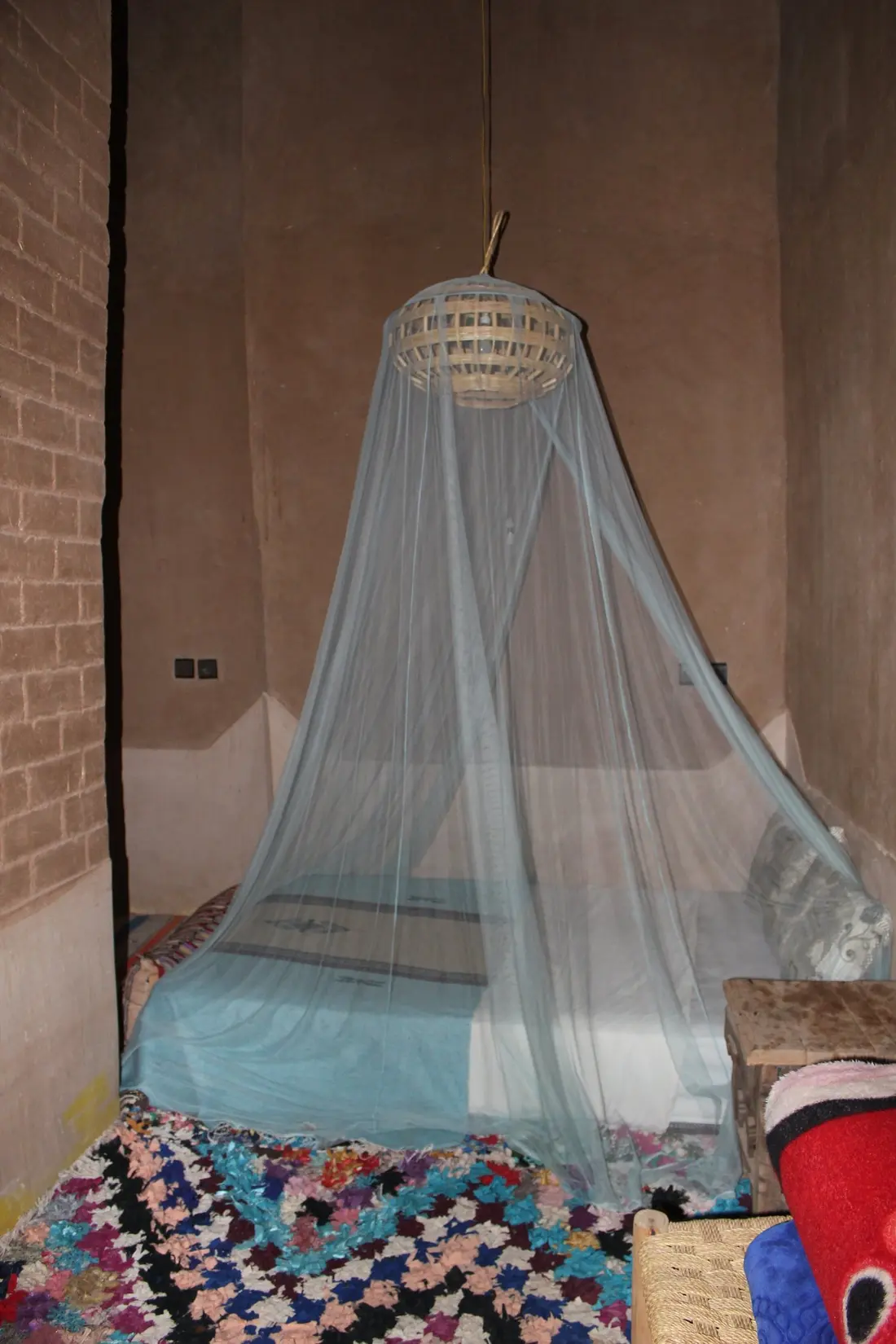 A bed beneath a canopy, behind rammed-earth walls