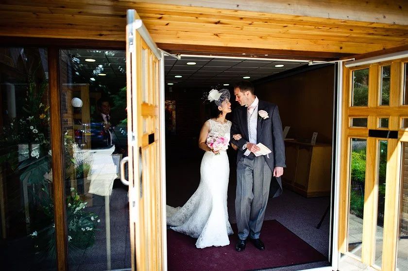 A bride and groom stepping out through the doorway, Le Manoir aux Quat'Saisons