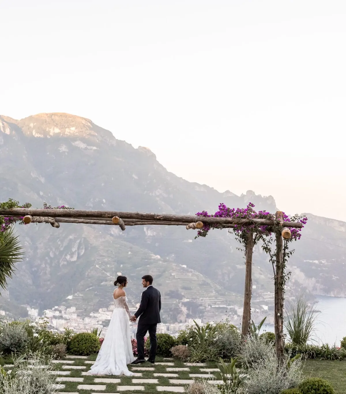 A pergola on a clifftop terrace, the coast and the sea below at dusk
