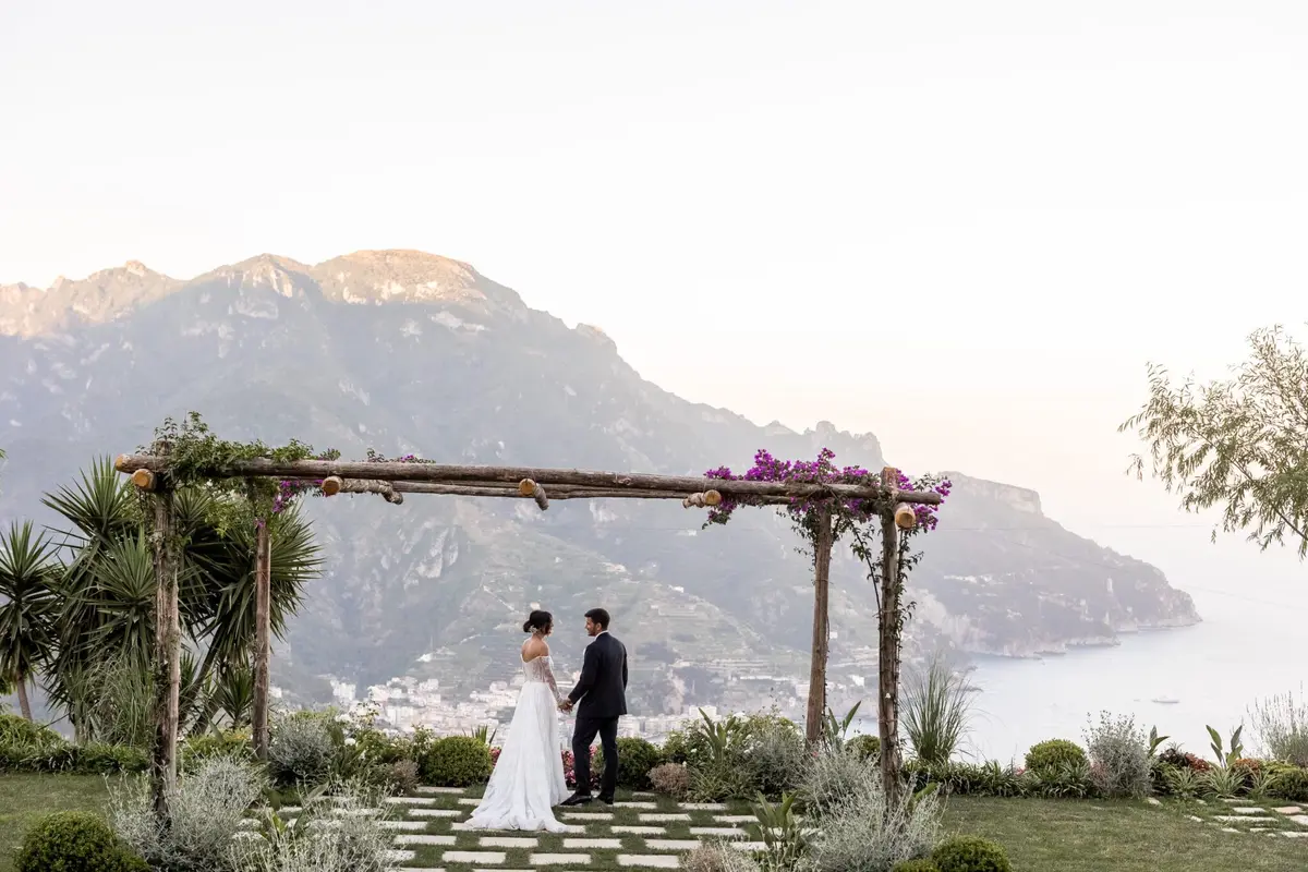 A pergola on a clifftop terrace, the coast and the sea below at dusk