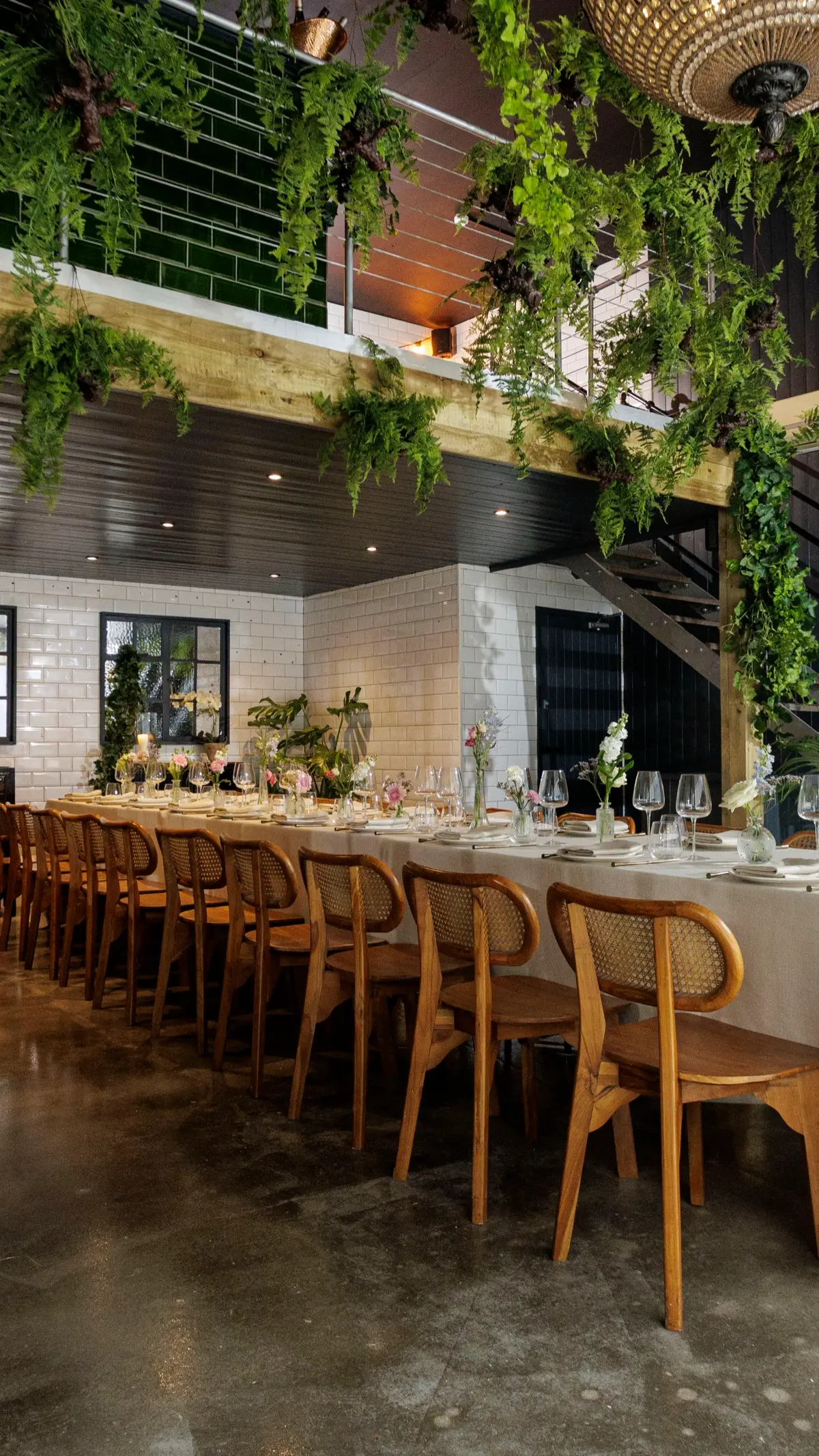 The City greenhouse, long table under foliage with the mezzanine stair