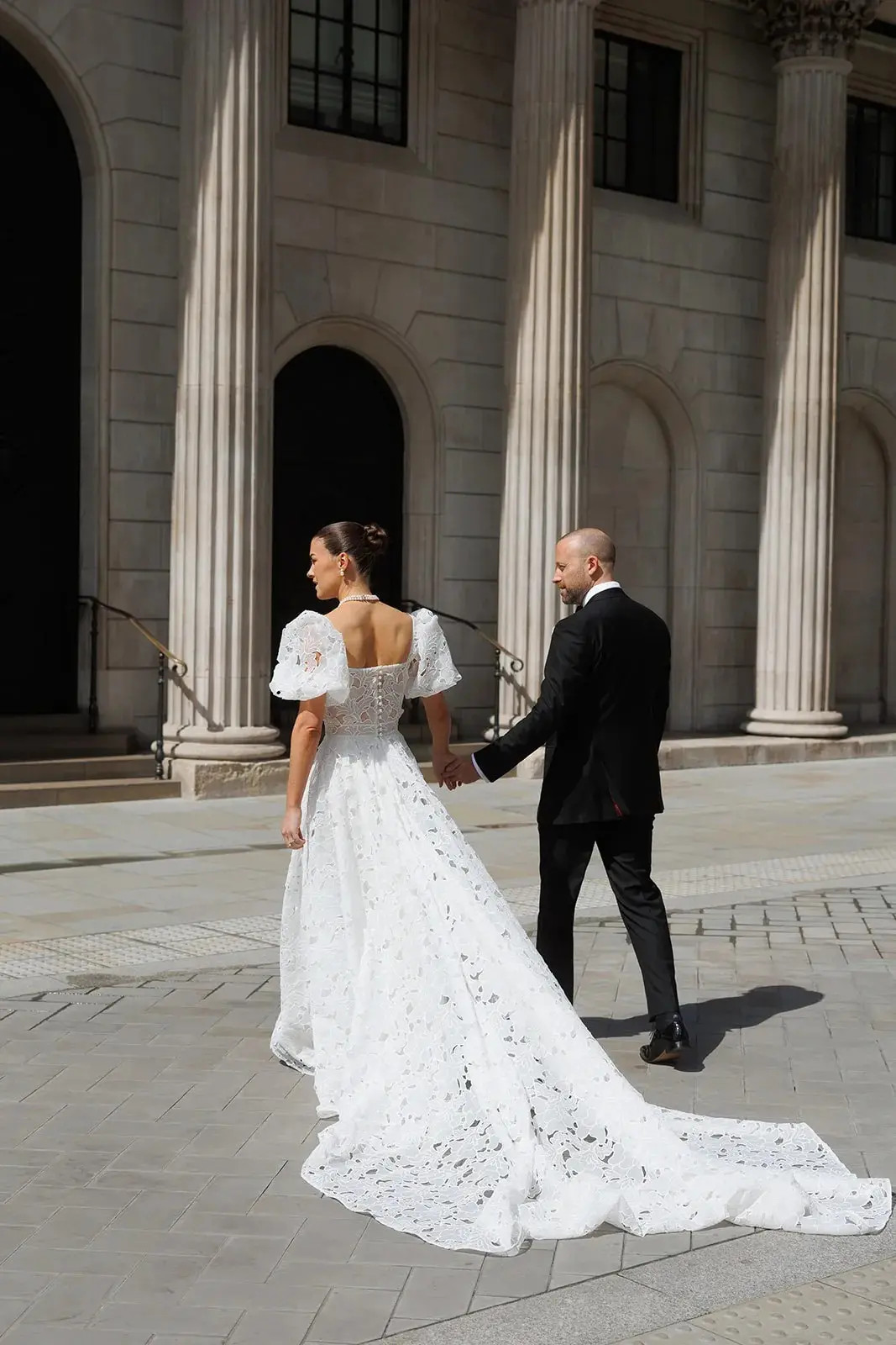 Emily and John, hand in hand beneath the colonnade, The Ned, Sweet Pea Floral Design, Hackney, England