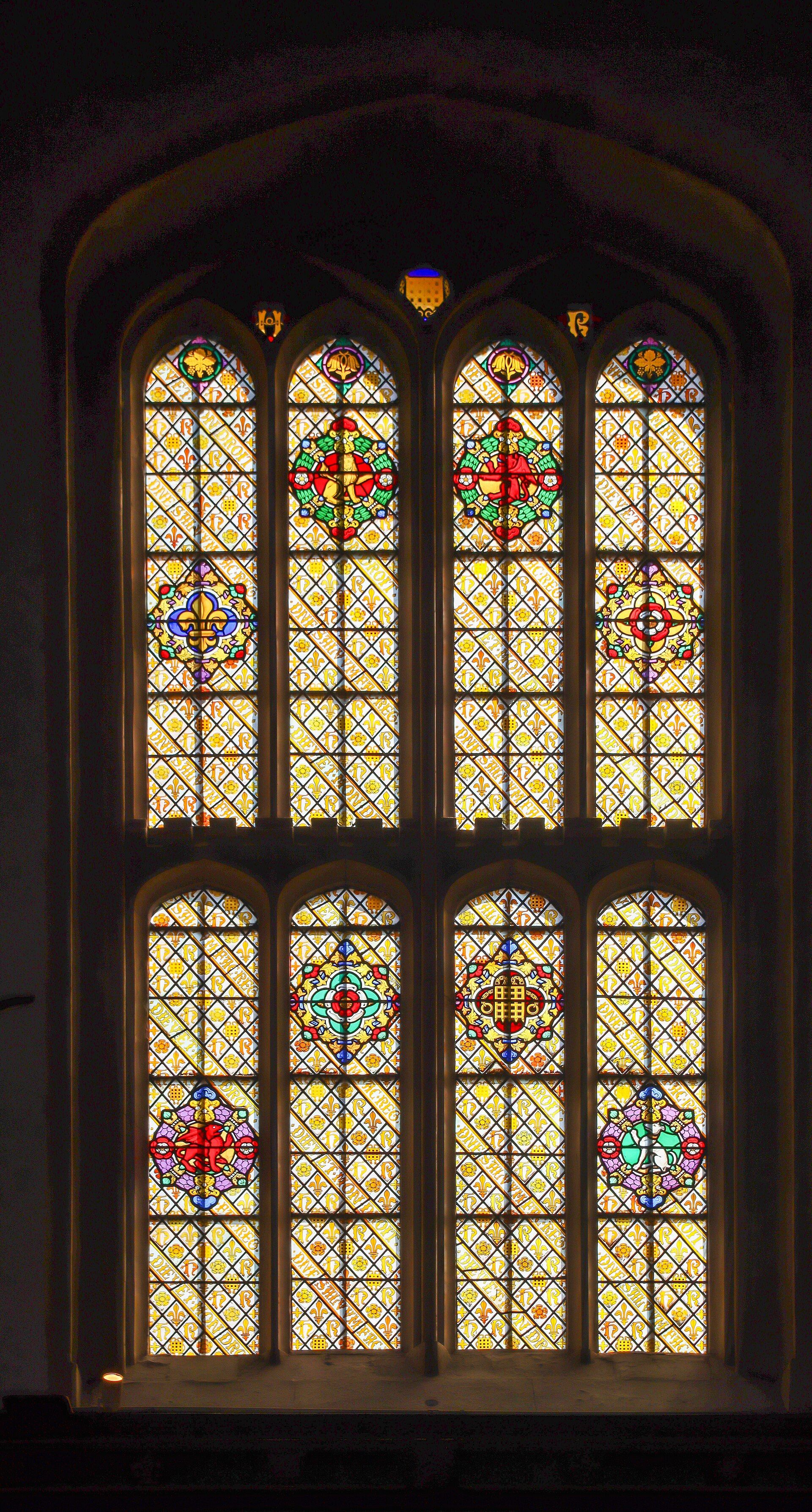A tall Gothic window, heraldic panels lit from without