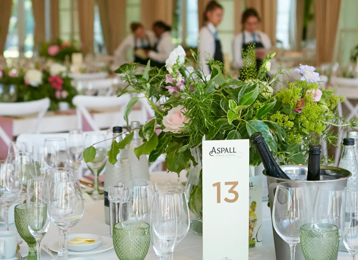 A wedding breakfast table laid with green glassware and a garden centrepiece