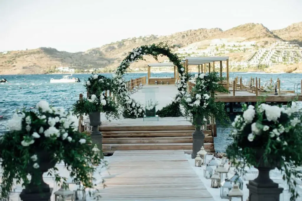 A circular floral arch on the jetty, framing the turquoise bay for a ceremony over the Aegean, The Bodrum EDITION, Bodrum, Turkey