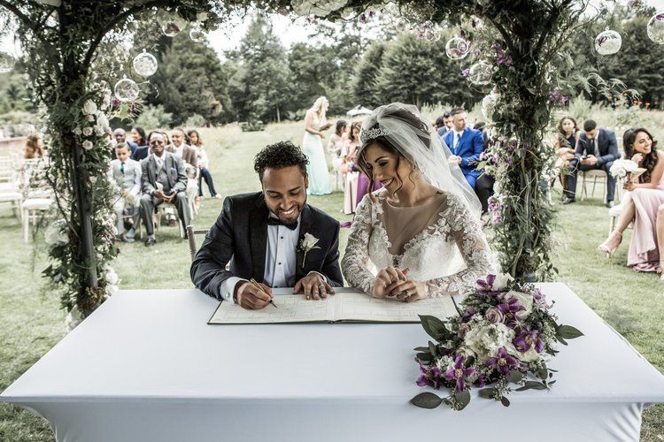 A couple signs the register beneath a floral arch, In Water Flowers, London, England