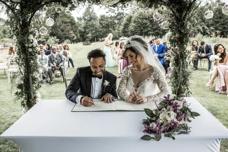A couple signs the register beneath a floral arch, In Water Flowers, London, England