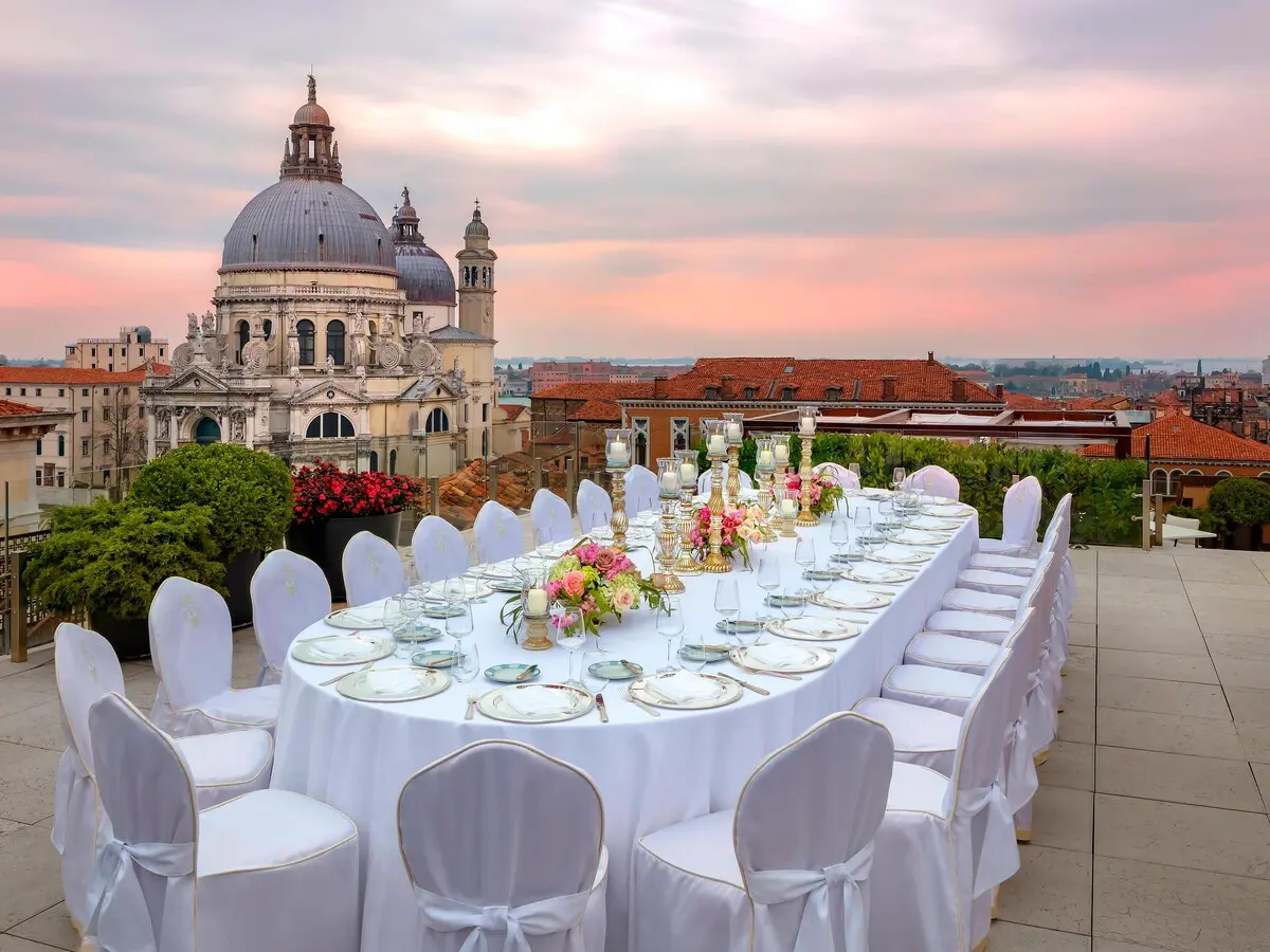 The Redentore rooftop terrace dressed for a wedding banquet at sunset, Santa Maria della Salute beyond, The Gritti Palace, Venice, Italy
