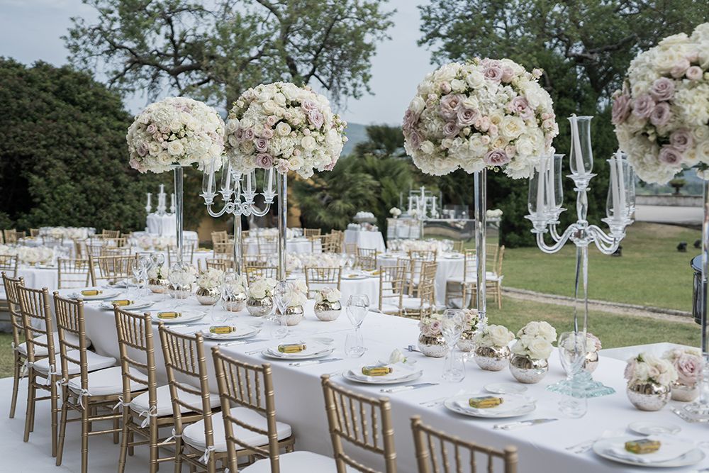 An outdoor reception, blush centrepieces beneath the trees