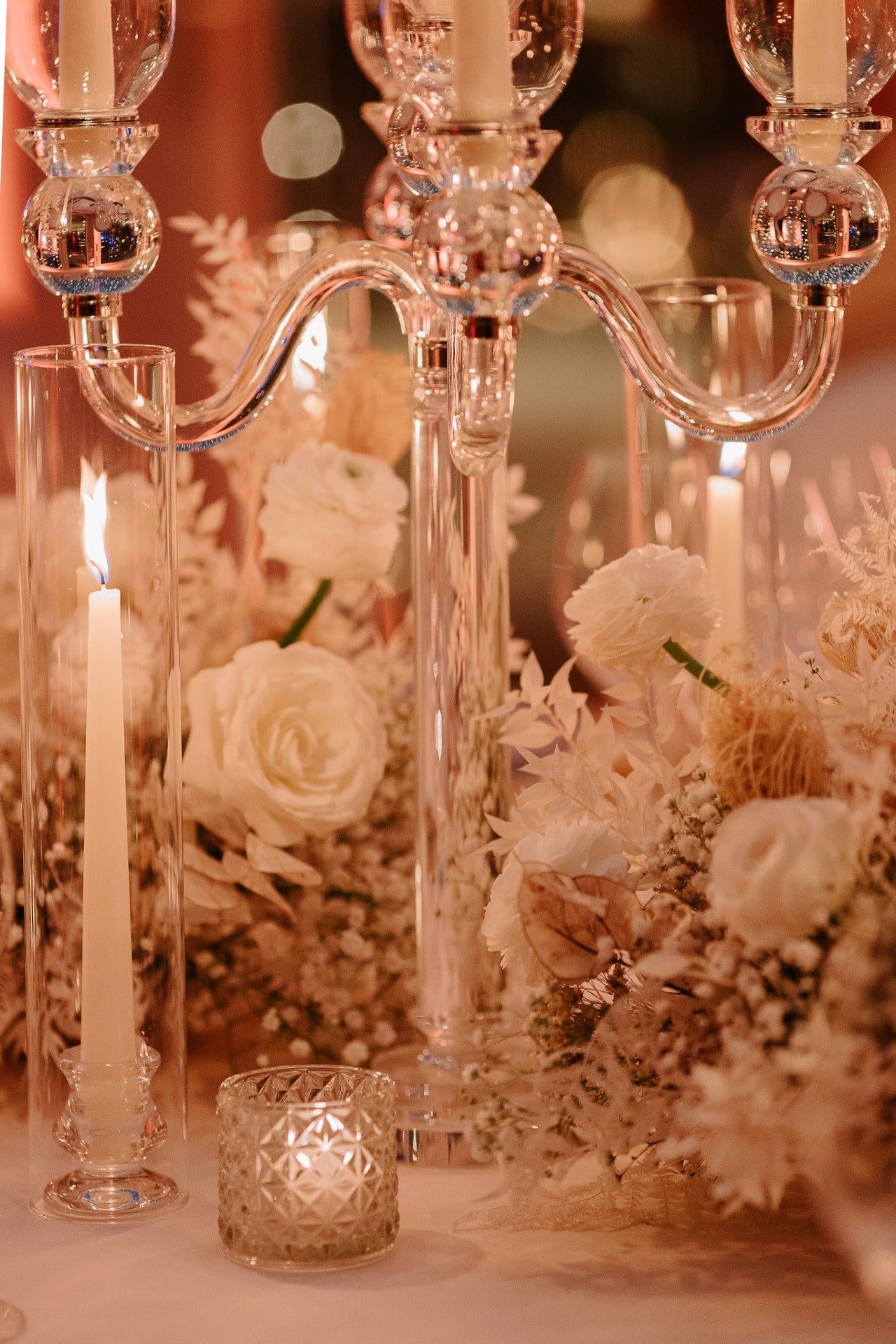 A glass candelabra dressed with white rose and dried grasses, Le Manoir aux Quat'Saisons. Photography by Harper Evans