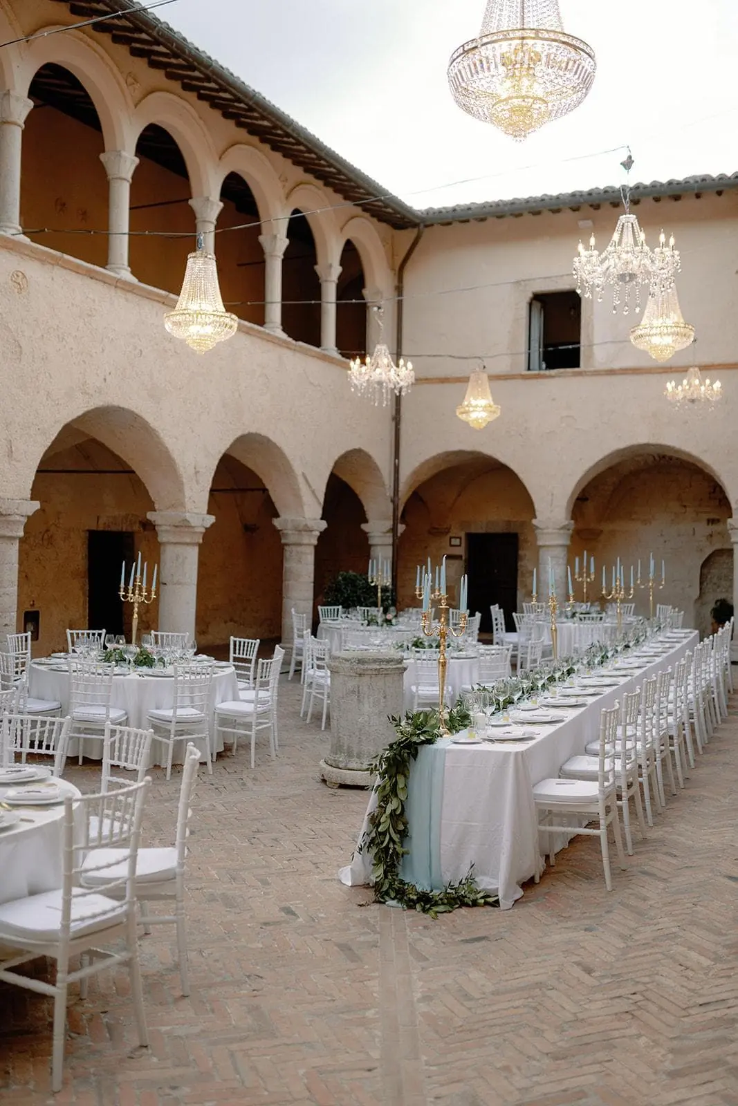 The abbey cloister laid for dinner under chandeliers