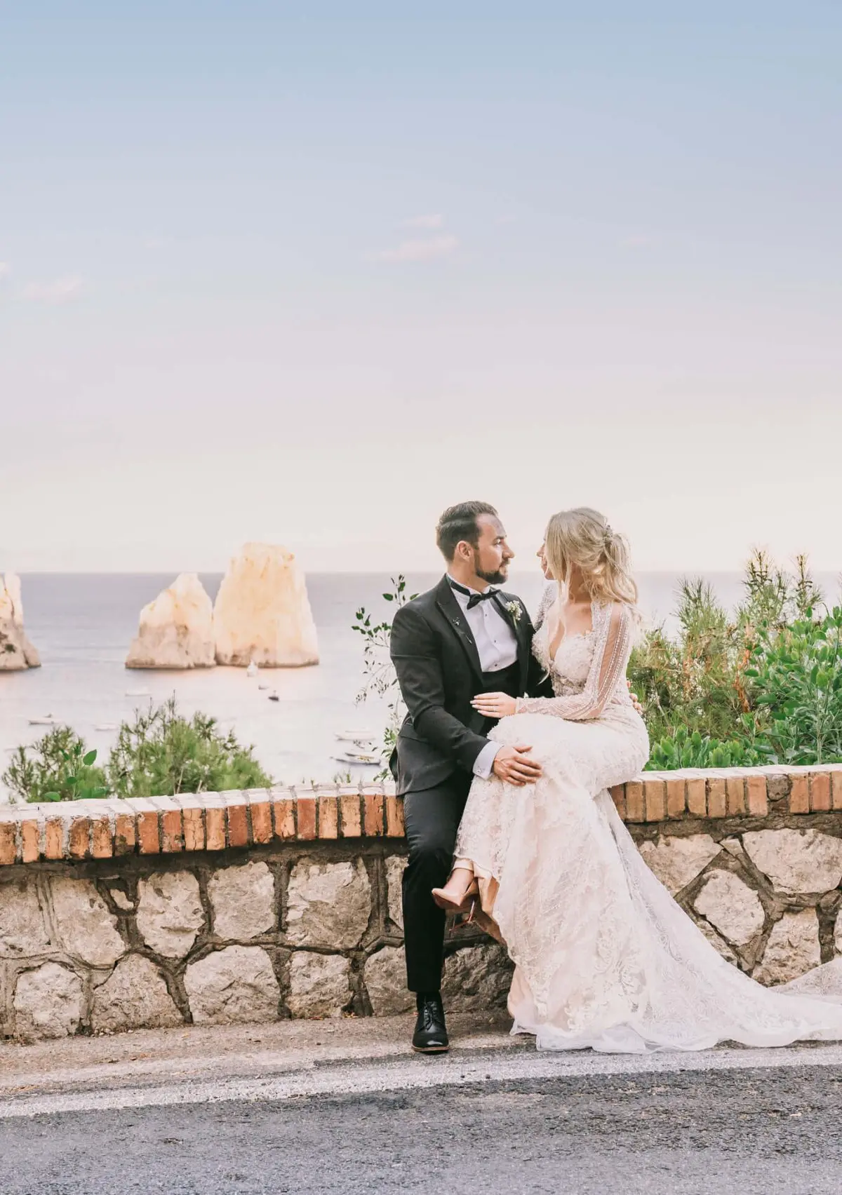 The couple on a coastal wall at golden hour, the stacks offshore behind them