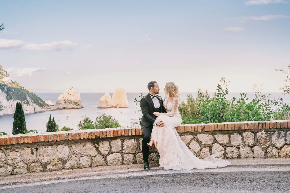 The couple on a coastal wall at golden hour, the stacks offshore behind them