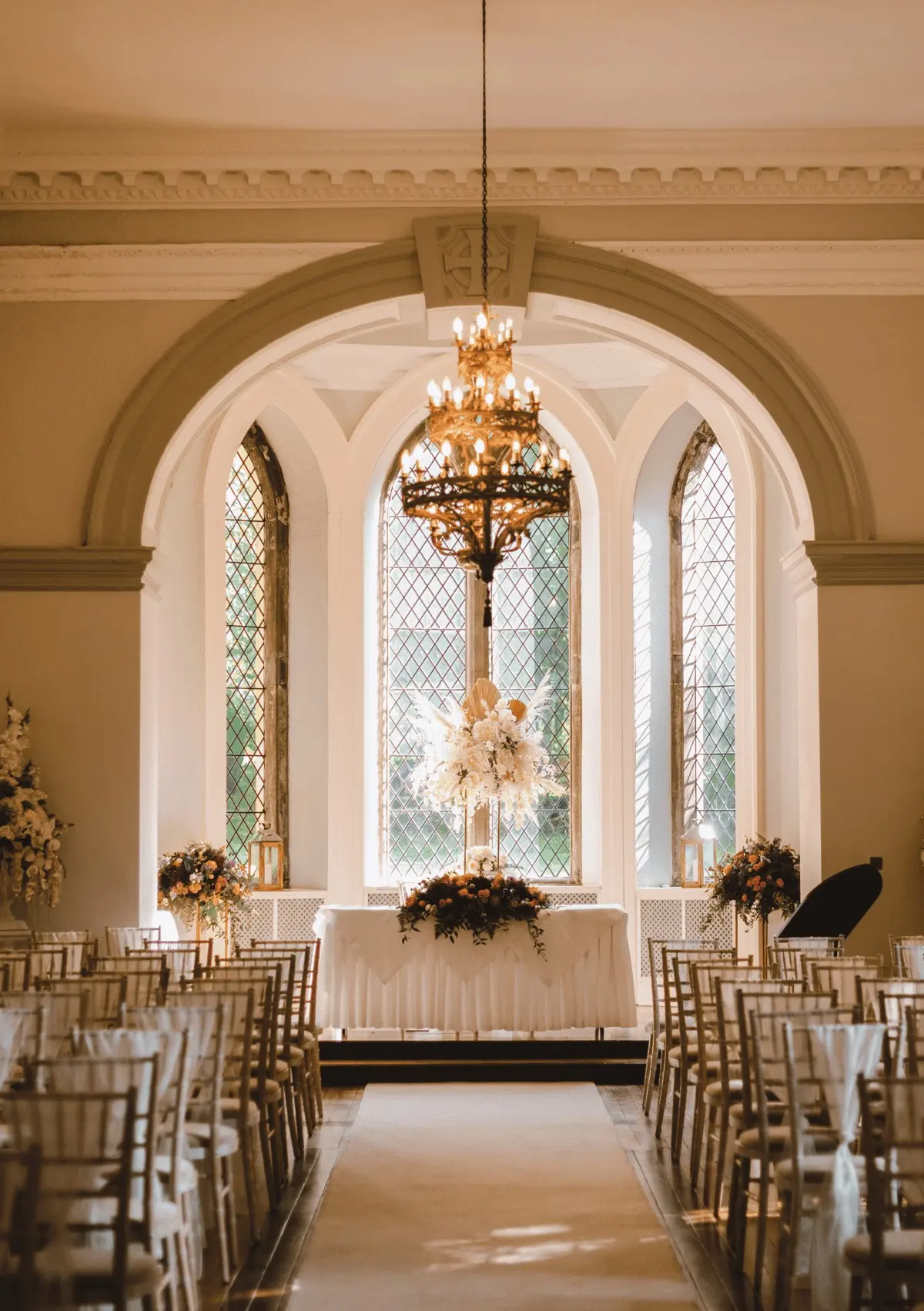 The Ballroom set for a ceremony, chandelier and tall arched leaded window